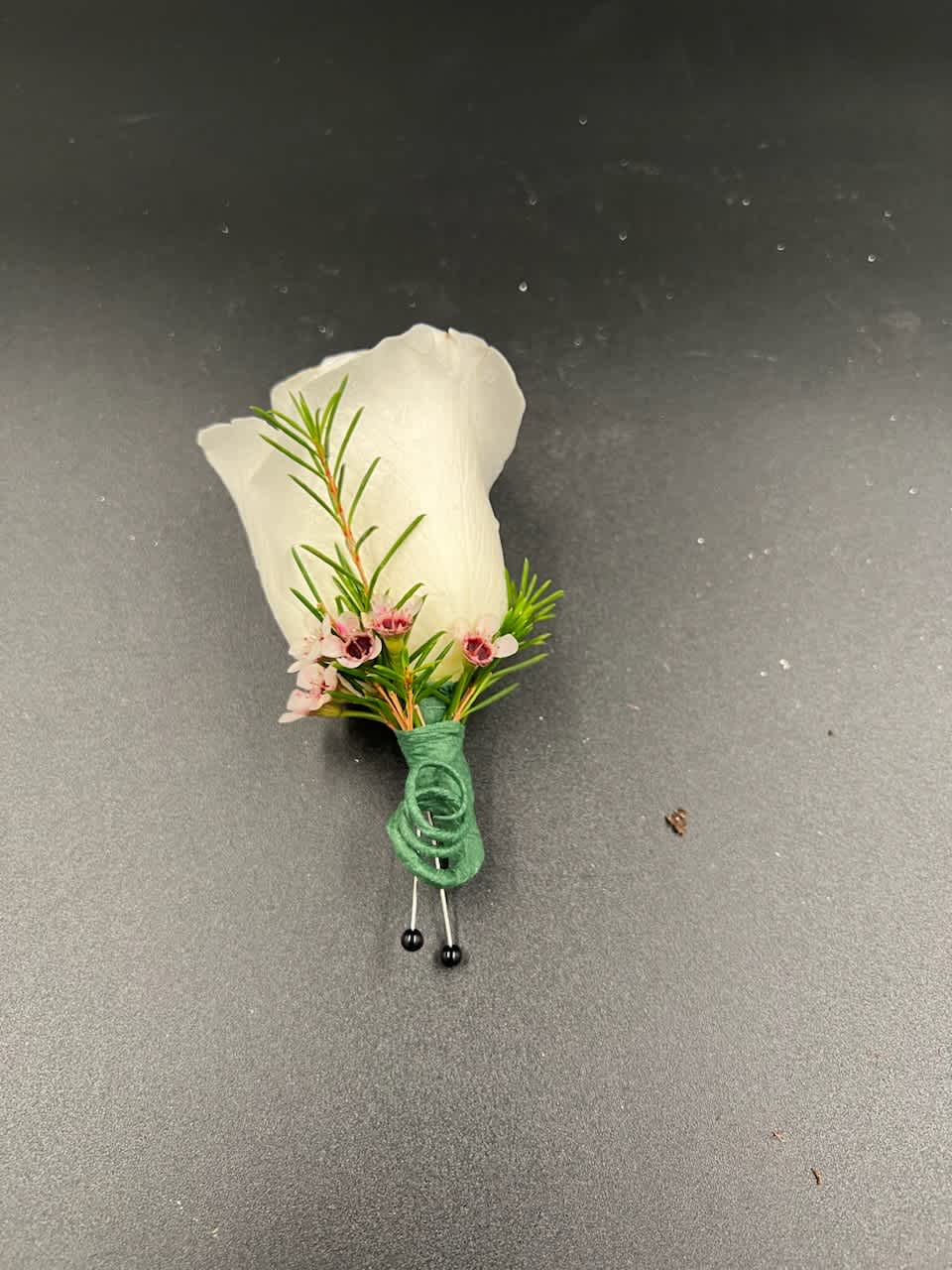 Rose Boutonnière  - A classic boutonnière that compliments any suit. Please include a color request with your order, the most common color for a boutonniere by far is white. The small accent flowers and greenery can vary.  The sale is limited time only!