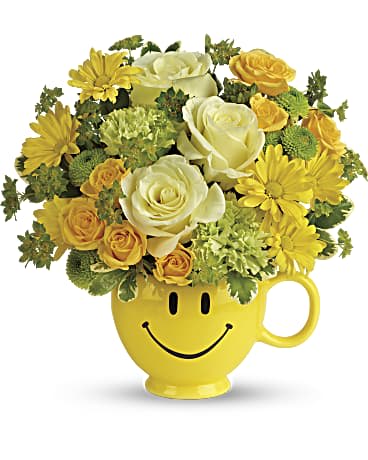 Teleflora's You Make Me Smile Bouquet - Put a smile on their face - and in their heart - with this happy as can be bouquet! Hand-delivered in a food safe mug for years of satisfied sipping, this cheerful gift of roses and mums spreads happiness wherever it goes. This cheerful bouquet includes light yellow roses, yellow spray roses, green carnations, green button spray chrysanthemums, yellow daisy spray chrysanthemums, bupleurum and variegated pittosporum. Delivered in a Be Happy mug.