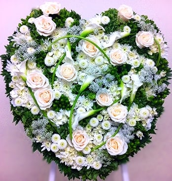 Peaceful Garden Closed Heart - This garden mix closed heart is a lovely mix of whites, ivories, and lush greens. Includes roses, button poms, Queen Anne's lace, hypericum berries, and cushion poms with white calla lilies intertwined. 