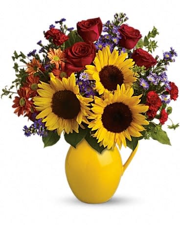 Sunny Day Pitcher of Joy - Symbolizing warmth and happiness, it is no wonder the sunflower is a quintessential ingredient in so many fall bouquets. This bouquet maximizes the joy of sunflowers by arranging them with a bevy of fall flowers, it's a lovely pick-me-up for a crisp fall day. Sunny sunflowers, red roses and miniature carnations, bronze daisy spray chrysanthemums, large lavender monte cassino asters and autumn greens are beautifully arranged in a ceramic vase. 