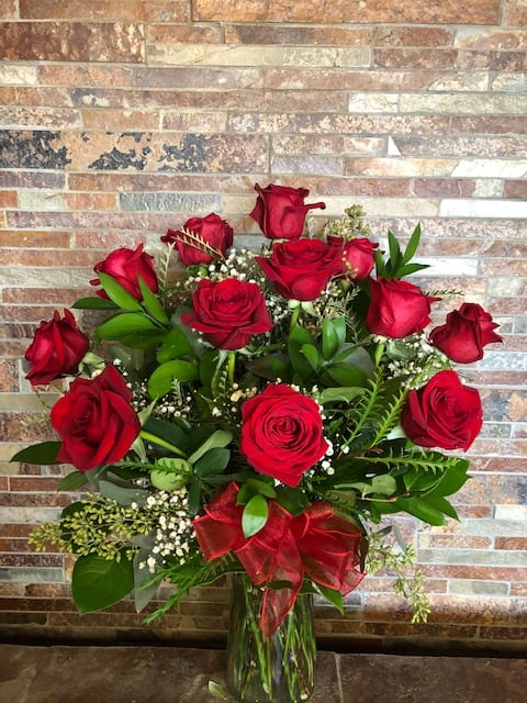 Classic Red Romance - 12 long stemmed, imported red roses designed with greens and filler in a glass vase. It's Classic, it's lovely, and it will sweeten up any day. Deluxe version features 18 long stemmed roses, and Premium will be 24, in a larger vase. 