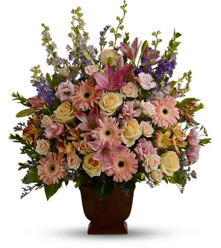  Loving Grace - A warm and peaceful bounty of pastel blossoms gently expresses love and respect that is appropriate for home or service. Fresh flowers such as peach and light pink roses lavender and purple larkspur pink lilies alstroemeria gerberas and lisianthus are set in an urn. Container substitutions may be necessary.