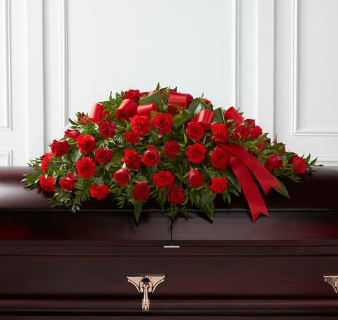 Tribute of Life Casket Spray  - The Tribute of Life Casket Spray bursts with the love and passion that the deceased had for their life and loved ones. Rich red roses and carnations are gorgeously arranged amongst lush greens and accented with a red satin ribbon to create the ideal adornment for their casket at their final farewell service.