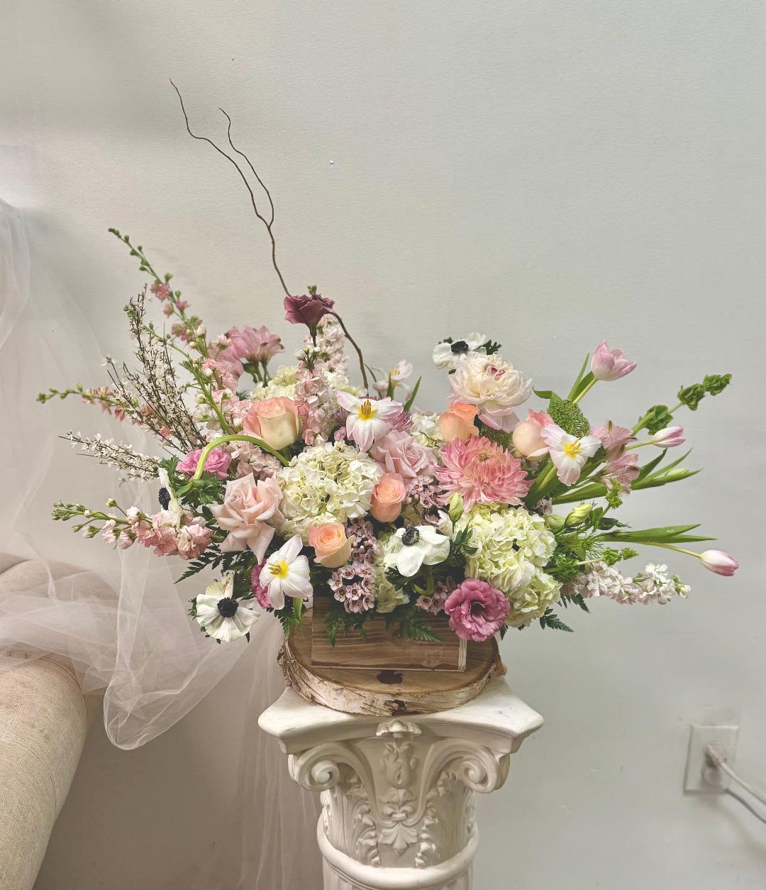 blush box - Product Information Theme Colors: Shades of white, pink, purple, Peach, and green  Arranged in a wooden box  Featured Blooms: Roses, Hydrangeas, Delphiniums, tulips poppy, stock Chrysanthemums, and greens  HK Flowers have a uniqueness of florals and seasonal blooms, certain flowers or colors may not be available as each season affects the availability, color, size, and shape of each floral bloom. Some flowers may be substituted accordingly.  Photos are used as a reference for the color palette and is NOT indicated of the final product. We ask for your trust in us that we will pick out the best seasonal available blooms, while still capturing the arrangements' theme and colors mentioned above.