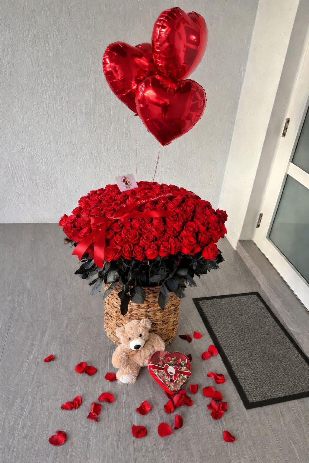 Luxury Red Roses Arrangement with Teddy &amp; Chocolates in a Basket - Make a bold and unforgettable statement with this over-the-top Valentine’s arrangement. Featuring a lavish dome of 150 premium red roses designed in a large woven basket, this piece is elevated with heart-shaped balloons, a plush teddy bear, and romantic finishing touches for the ultimate wow factor. Perfect for proposals, milestone celebrations, or when only the most dramatic expression of love will do.  This arrangement is designed to impress from every angle and is ideal for Valentine’s Day or any grand romantic gesture.  Very limited availability. Floral quantity and accents may vary slightly based on seasonal availability.