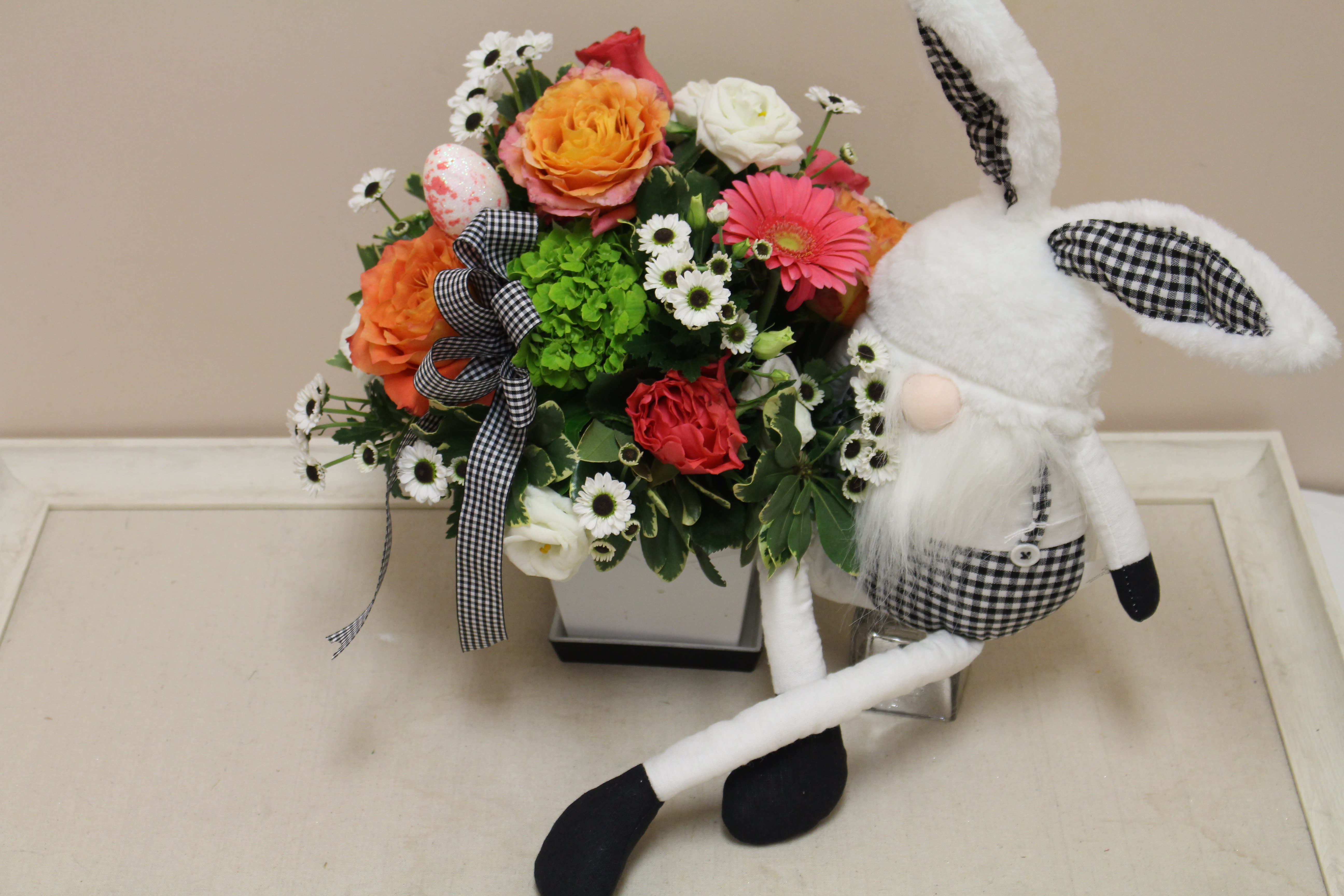 black and white gingham bunny gnome arrangement - This fresh arrangement includes spring blooms, including the sweet black and white daisy "ying Yang".  It is all accompanied by an adorable bunny gnome that can be taken out year after year.  The gift that keeps on giving.