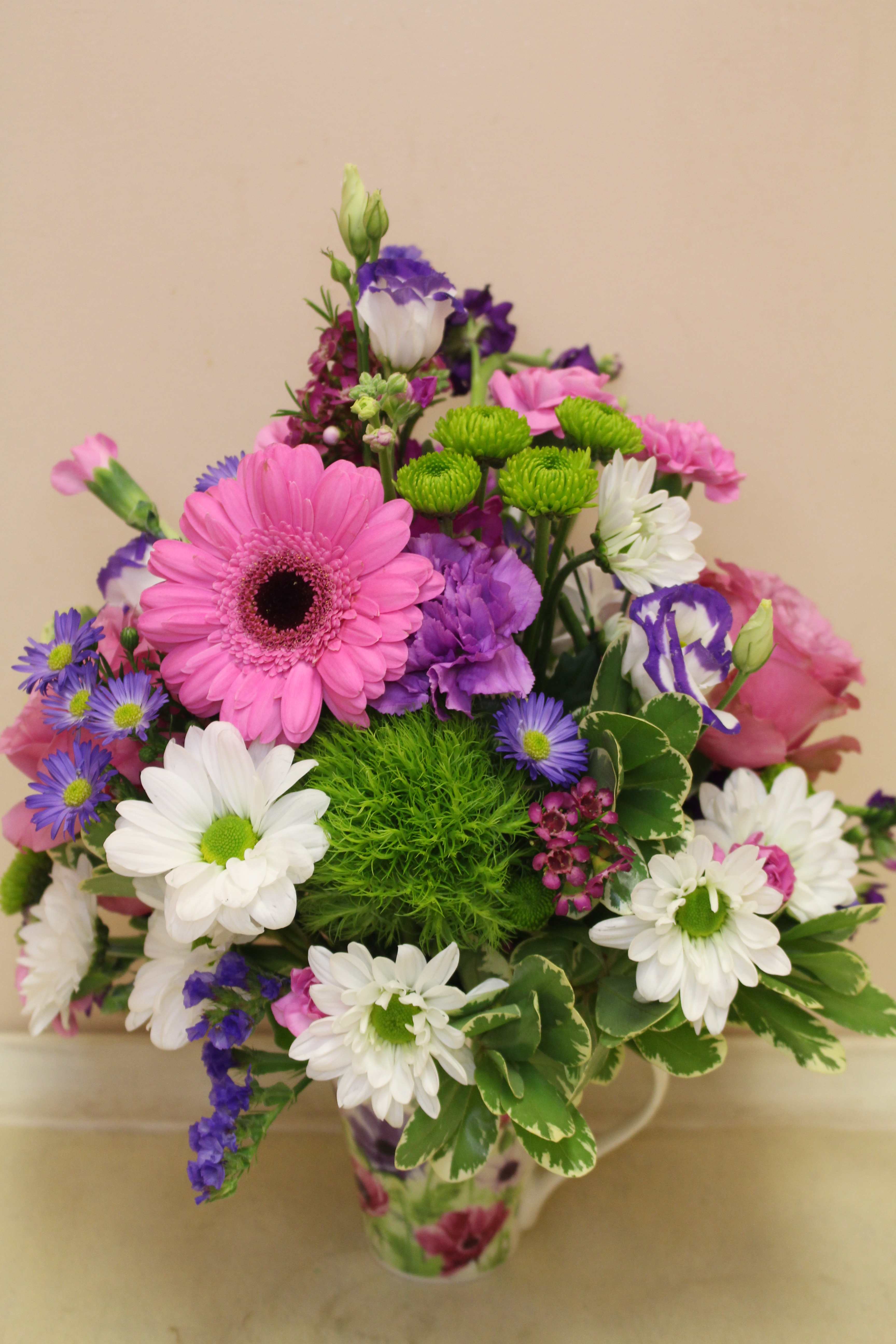 Latte of Wild Flowers - This arrangement invites you to imagine walking through a field of wild flowers while you sip your morning latte. Arranged in a tall coffee mug with an airy floral design, the bright mix of hydrangea, gerberas, spray roses, and other wild flowers this piece is perfect for any occasion. It's finished off with two butterflies that bring the peaceful feeling of a field straight to your door. 
