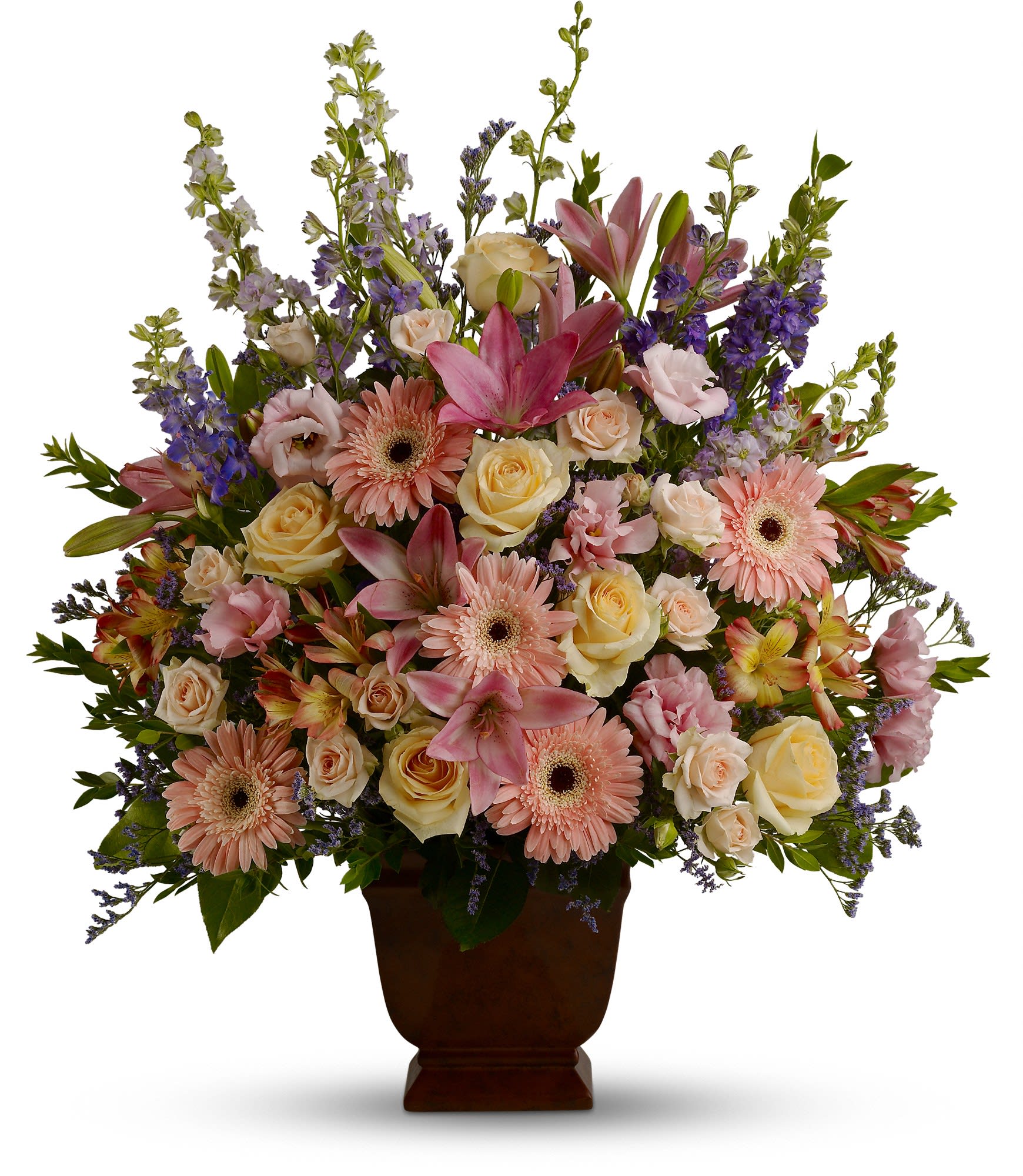 Teleflora's Loving Grace - A warm and peaceful bounty of pastel blossoms gently expresses love and respect. A gracefully composed arrangement appropriate for home or service.  Fresh flowers such as peach and light pink roses, lavender and purple larkspur, pink asiatic lilies, alstroemeria, gerberas and lisianthus are set in an exclusive Noble Heritage urn.  Approximately 26" W x 30" H  Orientation: One-Sided  As Shown : T220-1A
