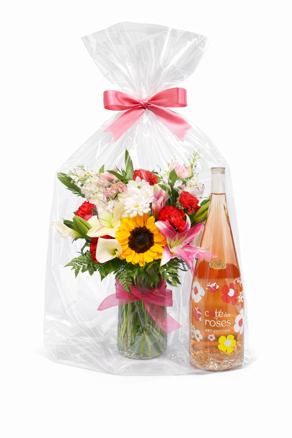 She Blooms Gift set - International Women’s Day Exclusive  Celebrate strength, beauty, and individuality with She Blooms, a radiant gift set designed to honor the incredible women in your life. This cheerful arrangement features a vibrant mix of fresh seasonal flowers including sunflowers, lilies, carnations, and daisies, artfully arranged in a clear glass vase. Paired with a bottle of Côte des Roses Rosé, the entire presentation is finished with elegant cello wrap and a soft pink bow—making it a perfect statement of appreciation, joy, and empowerment.  Perfect for honoring moms, daughters, sisters, friends, colleagues, and all women who inspire you.