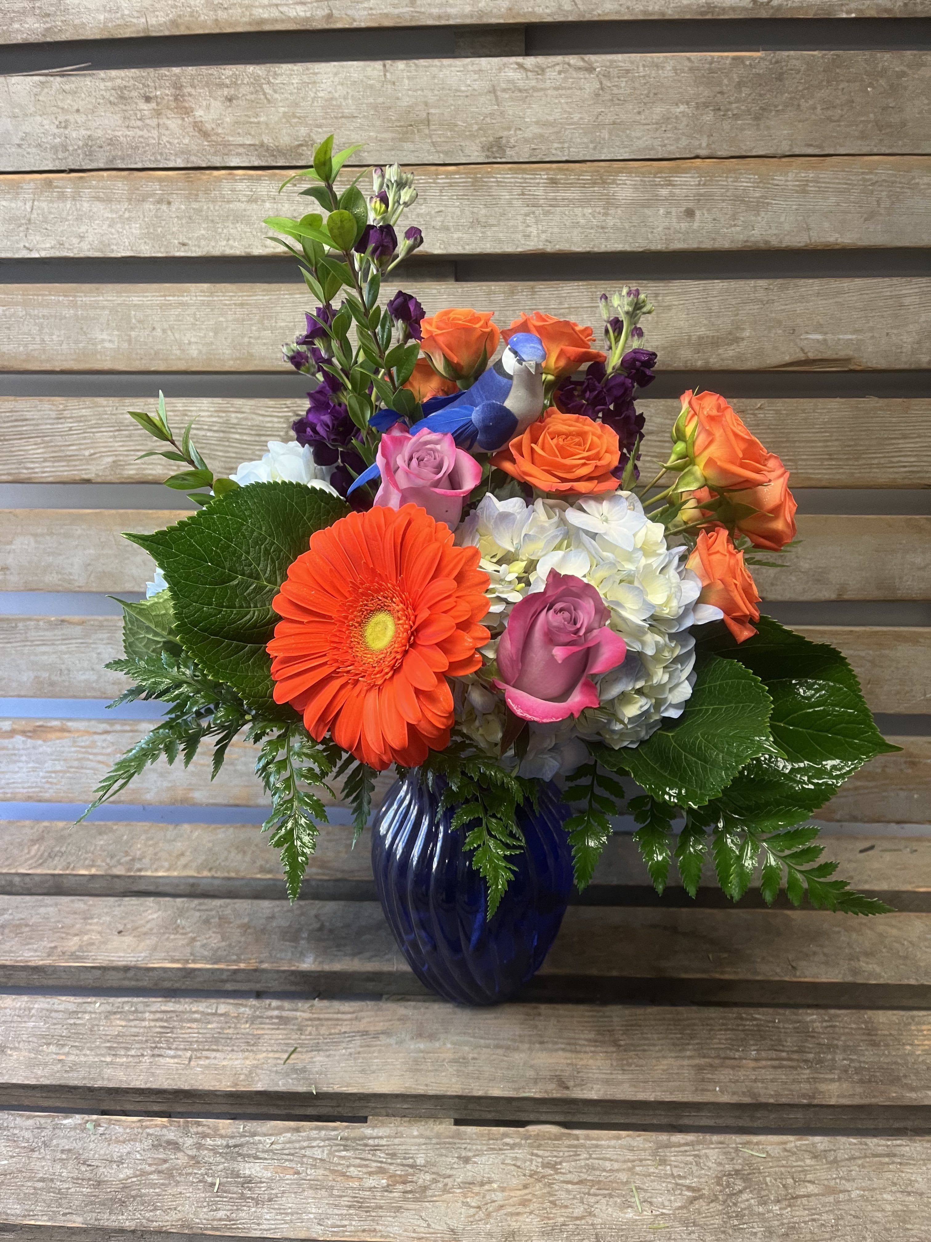 Spring bird arrangement - Cobalt blue vase filled with orange, blue, purple flowers. Accented with a adorable bird.