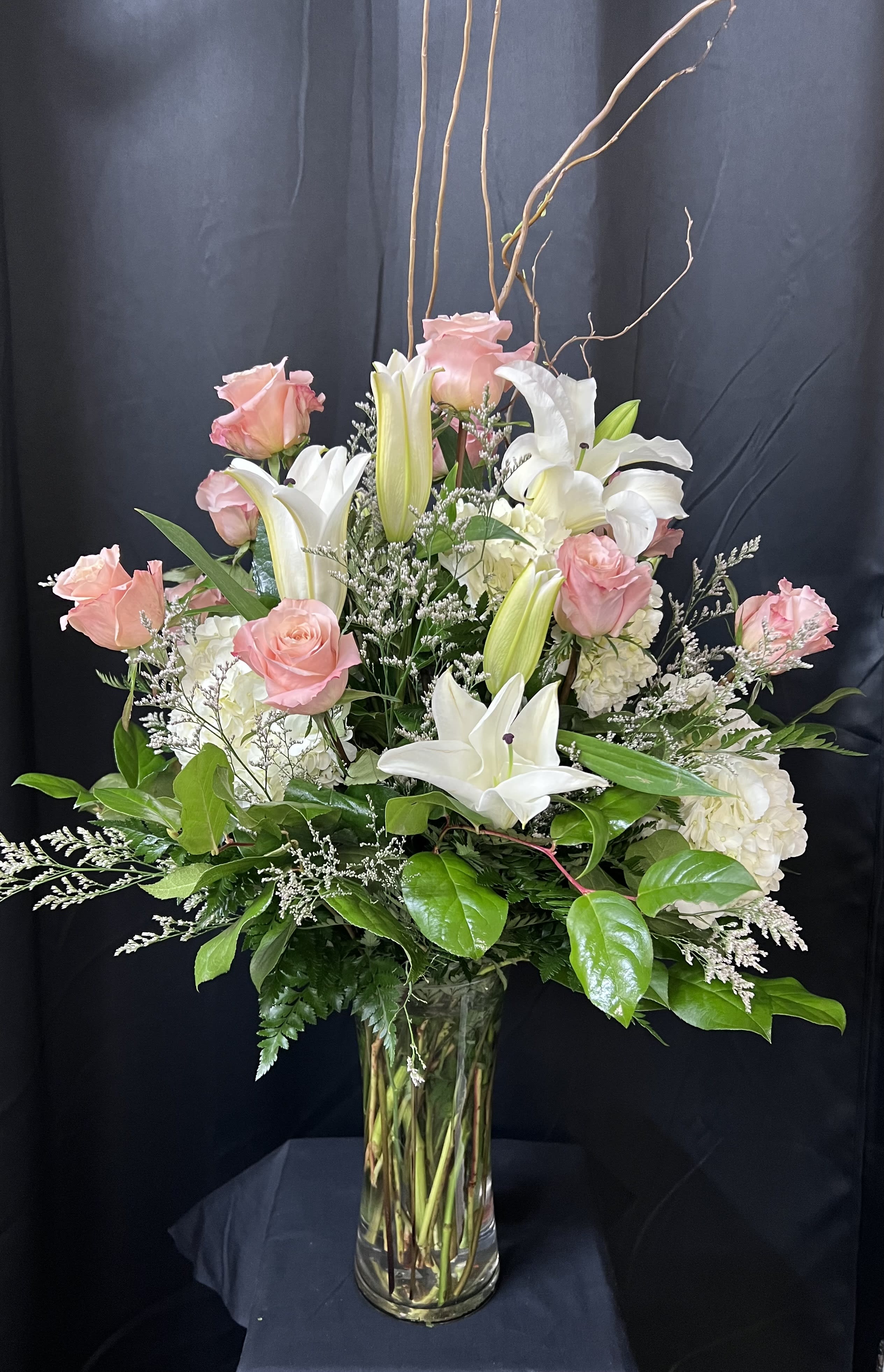Always a Lady  - A stunning gift like this one is always appreciated. An eye-catching display of roses, hydrangeas and lilies is perfectly arranged in a feminine vase which makes a beautiful and lasting impression.  Elegant white lilies and a sweet dozen pink roses are hand-arranged with white hydrangeas and greens. It's the perfect way to show you love her always and forever.  You can request the combination to be White Roses and Pink Lilies. If you like the look, but prefer a different color rose, please call and place your order. Orientation: All-Around