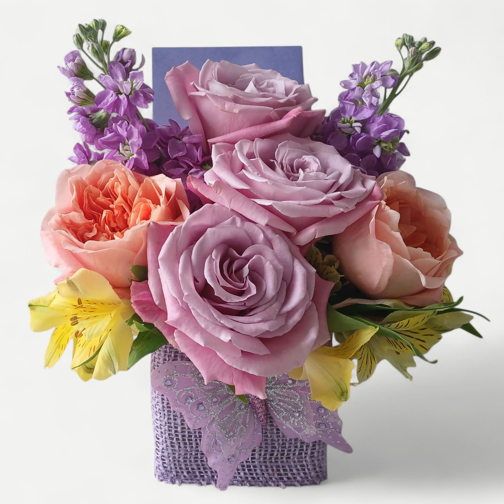 Violet Cutie Beauty Bouquet - Send this sweet size violet lavender bouquet today to make them smile with it's pretty blossoms of the day; roses stock and more arranged in a modern glass cube vase wrapped in lavender ribbon and adorned with a lavender sparkly butterfly. Pretty and perfect for every reason to show them how much you care. 