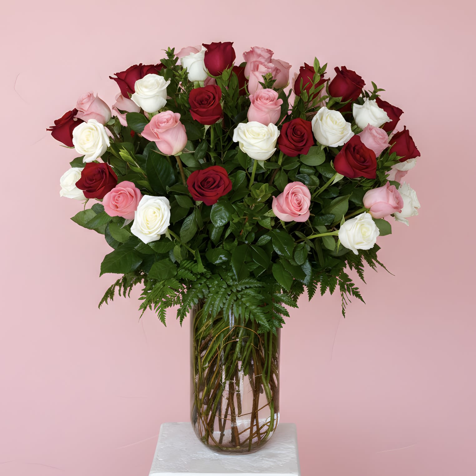 The Grand Romance - Make a grand romantic statement this Valentine’s Day with our stunning 50-stem rose arrangement, featuring a luxurious mix of red, white, and pink premium roses beautifully arranged in a clear glass vase with lush greenery. Designed to impress, this full and elegant bouquet symbolizes love, admiration, and lasting devotion, making it the perfect gift for a partner, spouse, or someone special.  Want a different color? Give us a call or write in the "Notes for the florist" section at checkout the color you prefer!  This deluxe Valentine’s rose arrangement creates an unforgettable moment and serves as a breathtaking centerpiece for the home or office. With fifty fresh roses hand-arranged for maximum impact, it’s an ideal choice for milestone celebrations, romantic surprises, or a truly memorable Valentine’s Day delivery.