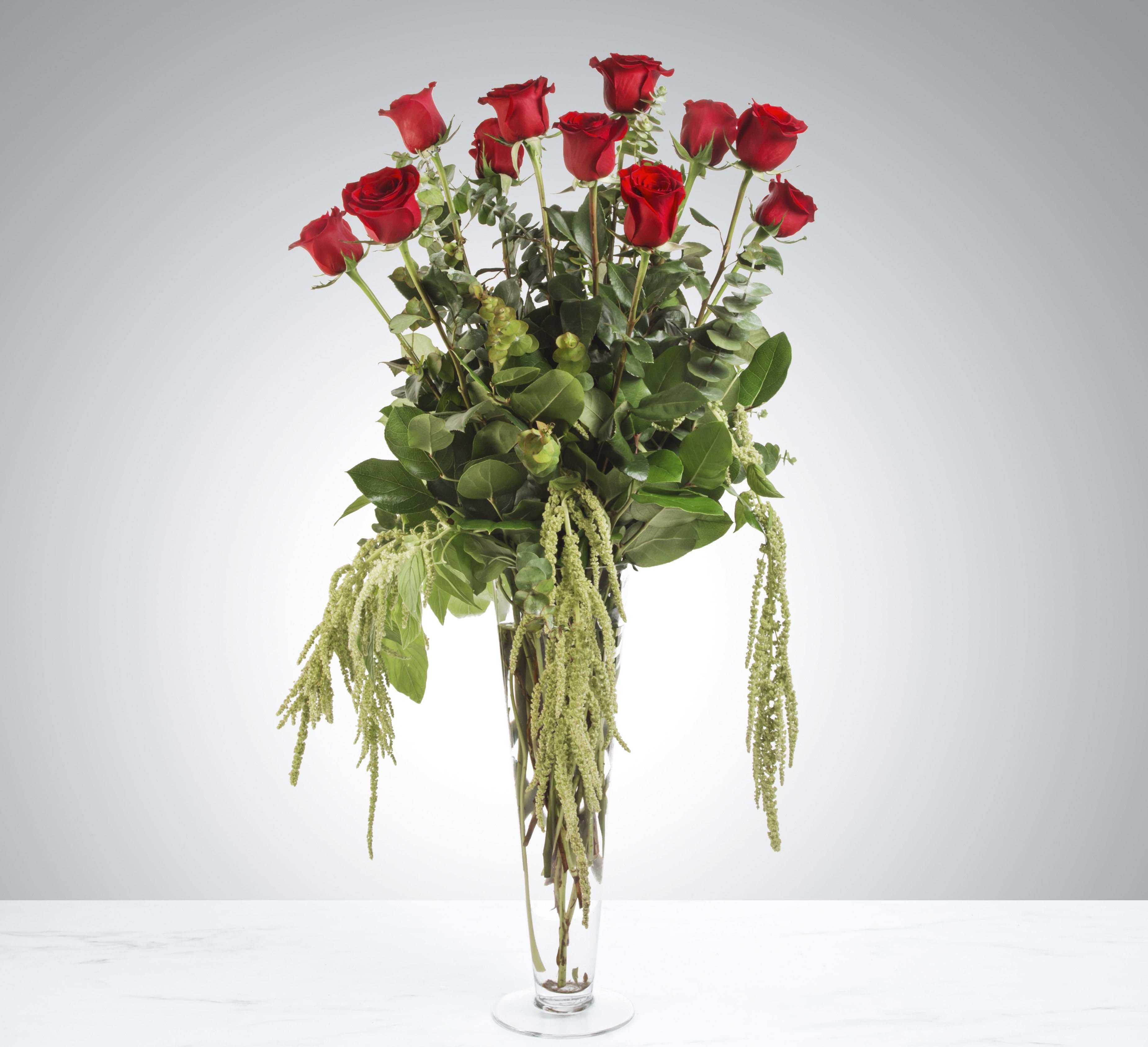 Forever Type of Love by BloomNation™ - Make a statement with this dramatic arrangement. With a tall vase and modern greens, this mix of the classic 12 dozen roses with a gothic romance twist stands the test of time. Perfect for valentines day, anniversaries, or any type of romance.   APPROXIMATE DIMENSIONS: 11" W x 25" H