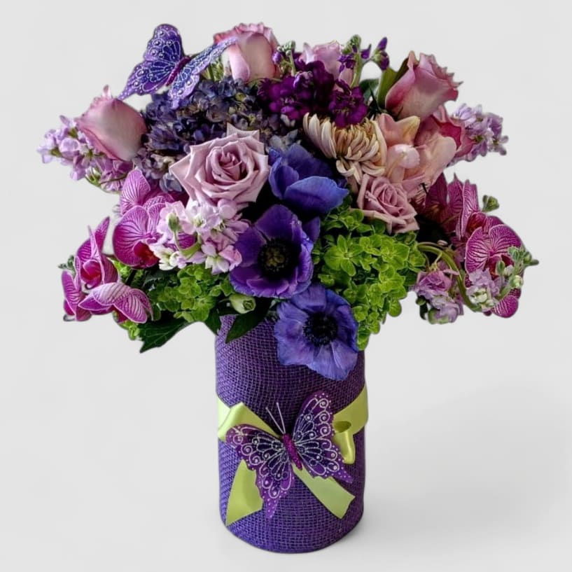 Violet Beautiful Bouquet Designer's Choice - Please call first for availability. Beautiful purple violet lavender blossoms roses orchids and more arranged in a tall modern glass cylinder vase wrapped with purple jute ribbon. Perfect to send today to make their day. Always made extra special and unique each time. Send happiness.