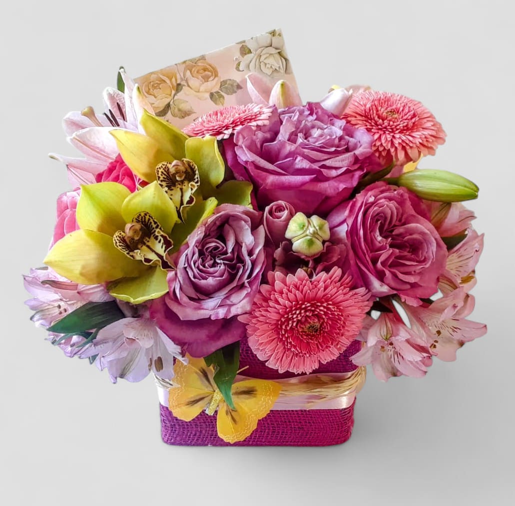 Purple And Pink Mixed Blossoms Beauty Designer's Choice - Made unique and different each time. Perfect for every occasion. Send this beauty today to show them how much you care with it's beautiful mixed pink, purple and green blossoms of that day roses orchids and more arranged in a modern glass cube vase wrapped in pretty pink jute ribbon. All flower design's that leave my studio are beautiful works of art. Send them happiness. Send them a special bouquet to make them smile.