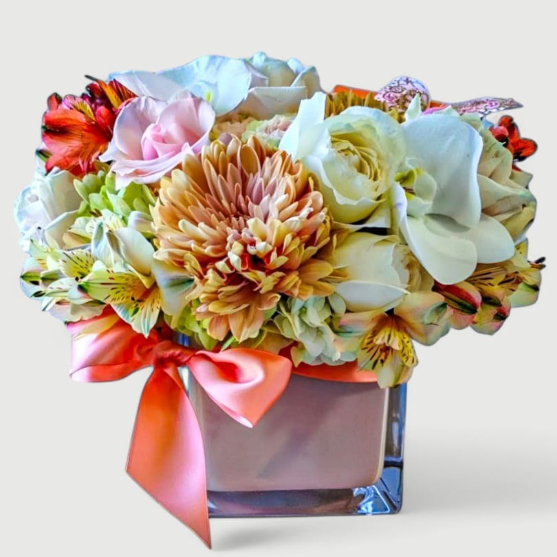 Vanilla Blush Beauty Designer's Choice - Designer's choice; made beautifully from my vanilla and peach blossoms of the day roses orchids and more arranged in a modern blush glass vase adorned with a lovely blush ribbon. Perfect to send for every occasion to make them smile. Send happiness.