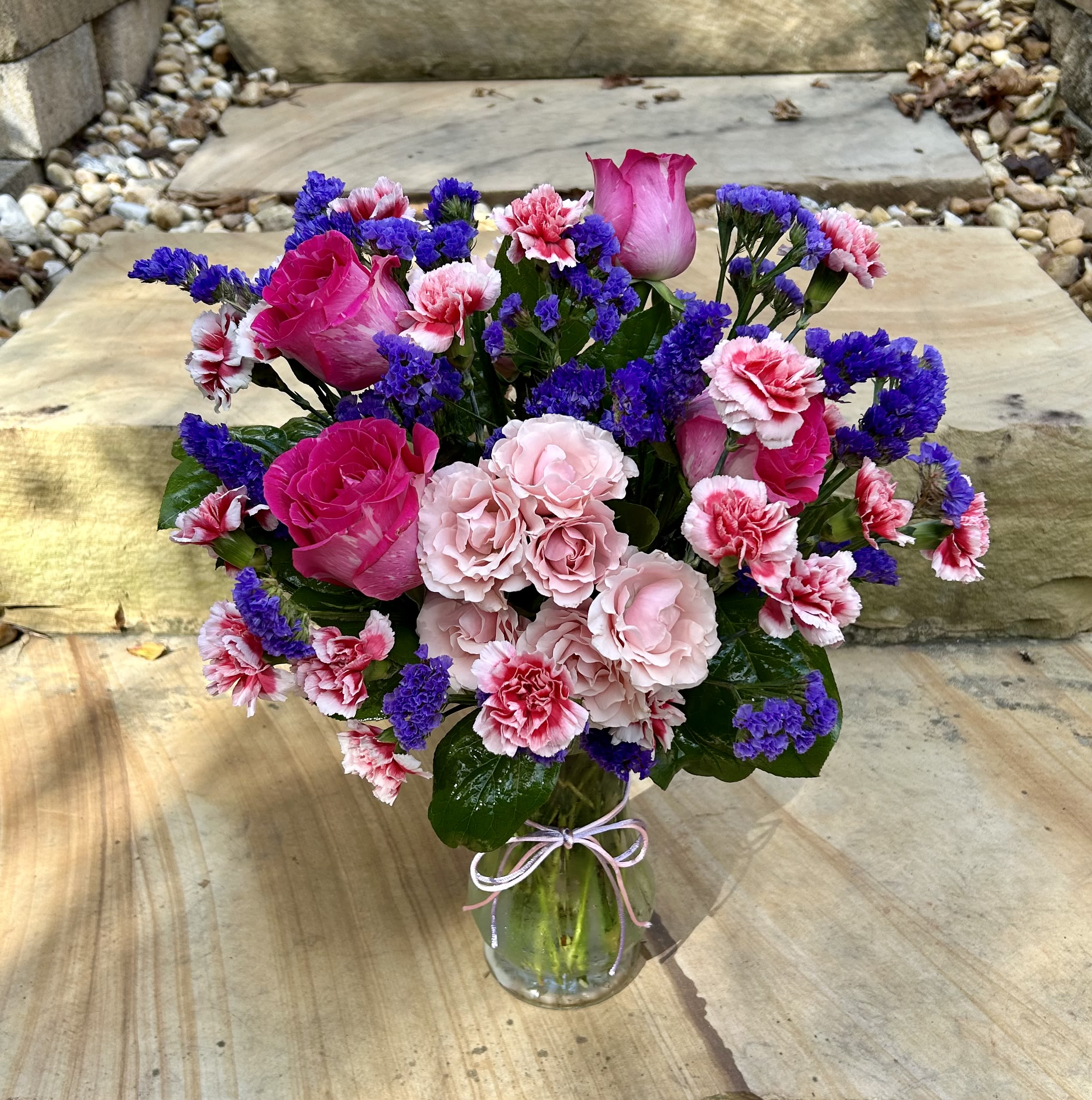 Beautiful Gem - A pink and purple arrangement of roses, mini carnations, spray roses and purple fillers with a pink and purple bow to finish the look.