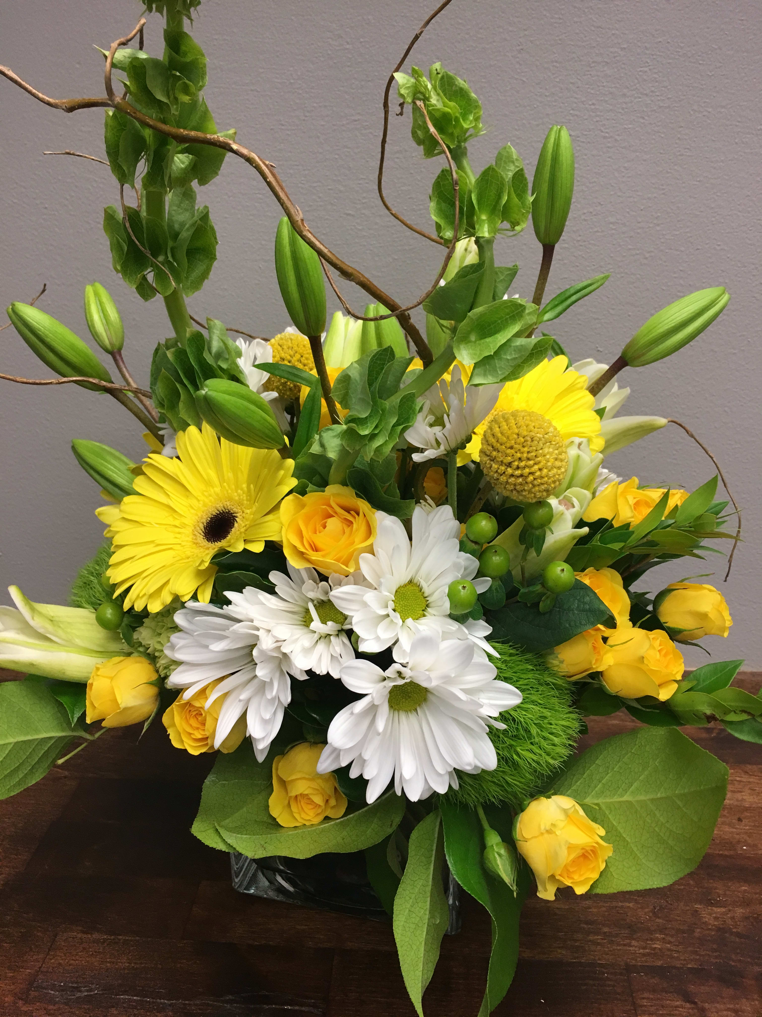 Squeeze the Day - This modern design with blooms in greens, white and yellow is a sweet reminder of the brightness of lemons and limes.  A great summer bouquet, full of fresh and bright bloomers, designed in a cube with curly willow accents.  We custom create each piece- based on availability and seasonality of flowers, and want each arrangement to be one of a kind.  Be assured- your arrangement will have the look and feel you've chosen.  Please feel free to leave comments for the designer you would like us to take into account in designing your unique arrangement.