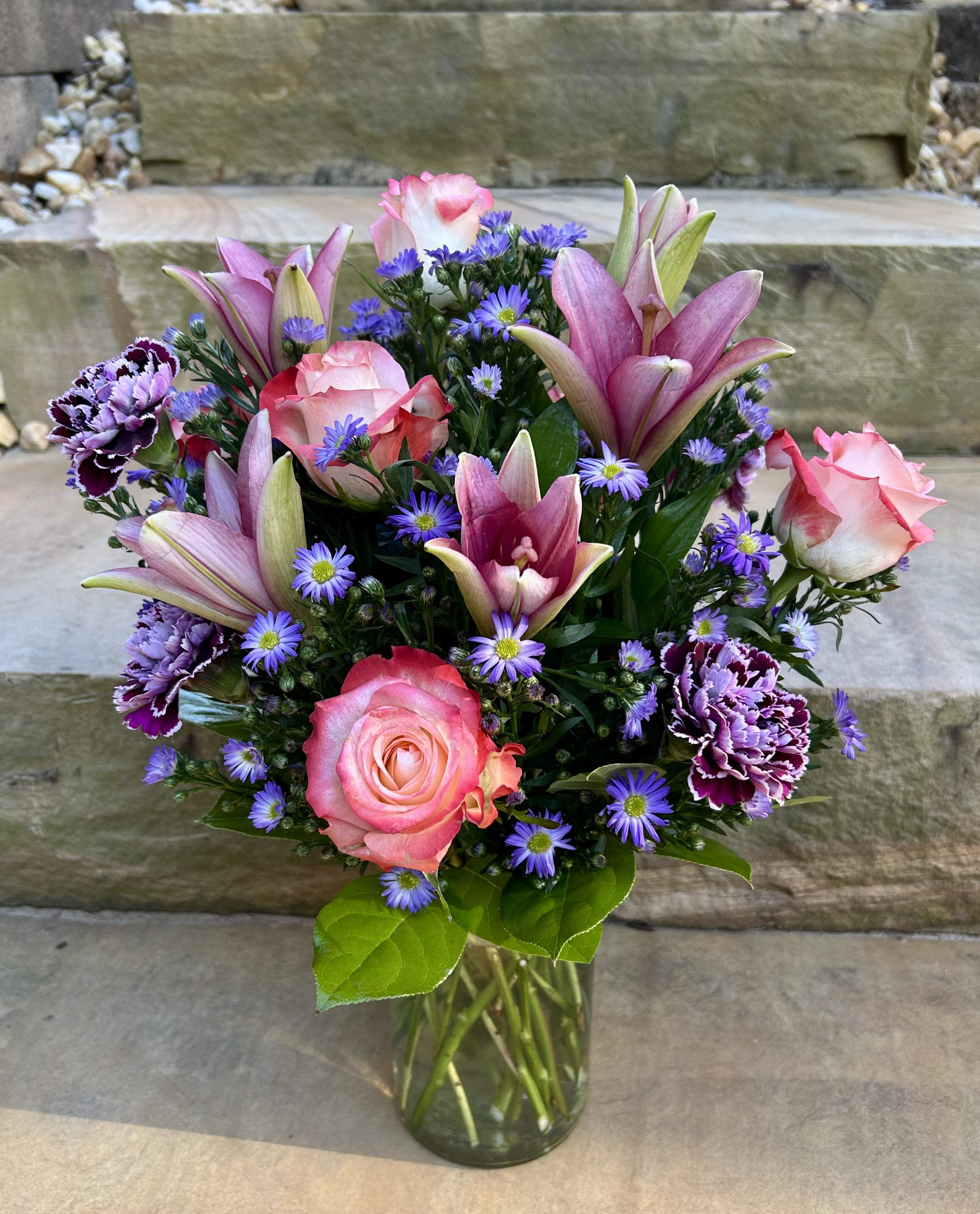 Spring Pastels - A pastel colored arrangement of different shades of pink and purple flowers — lilies, rose, carnations and filler flowers. 