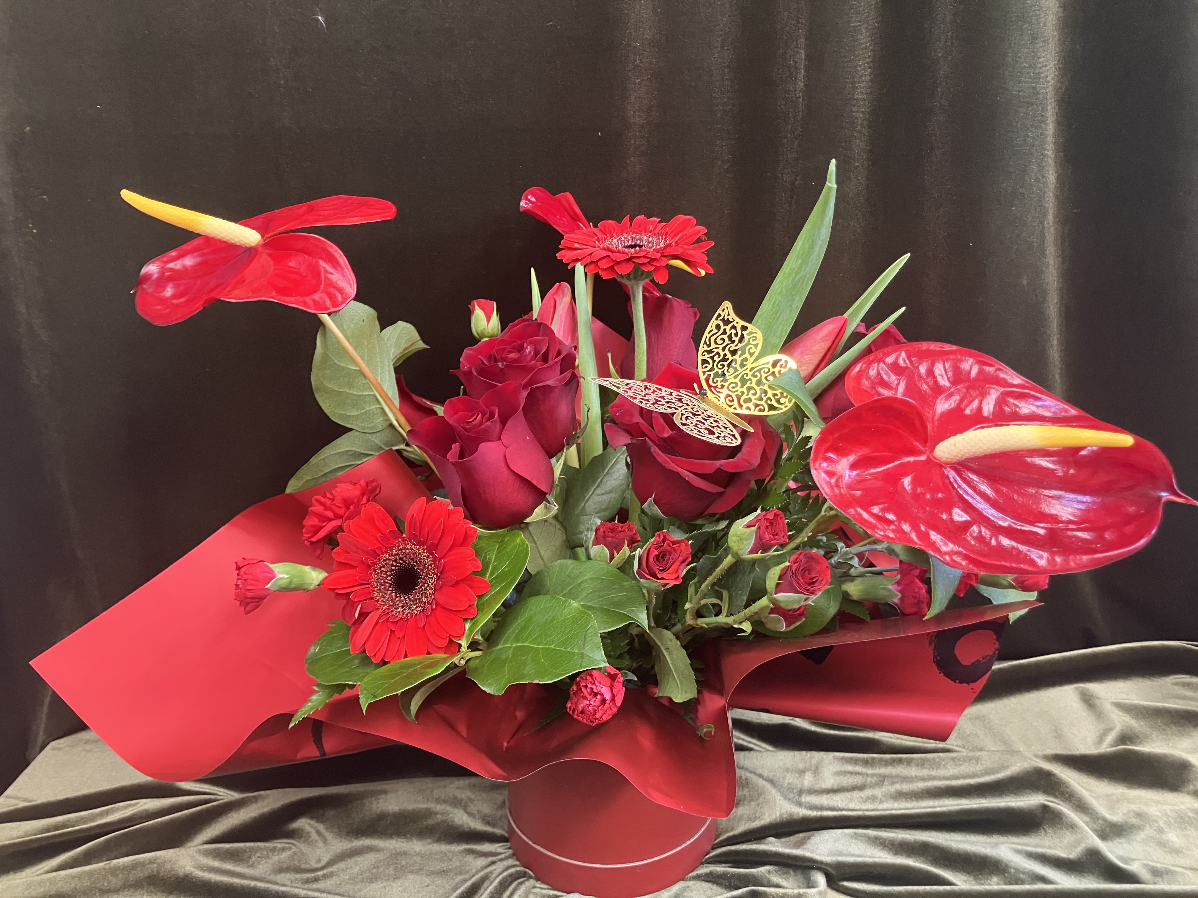 Stunning Red Barrel Arrangement  - Red rose arrangement in a red barrel container, with a decorative butterfly.