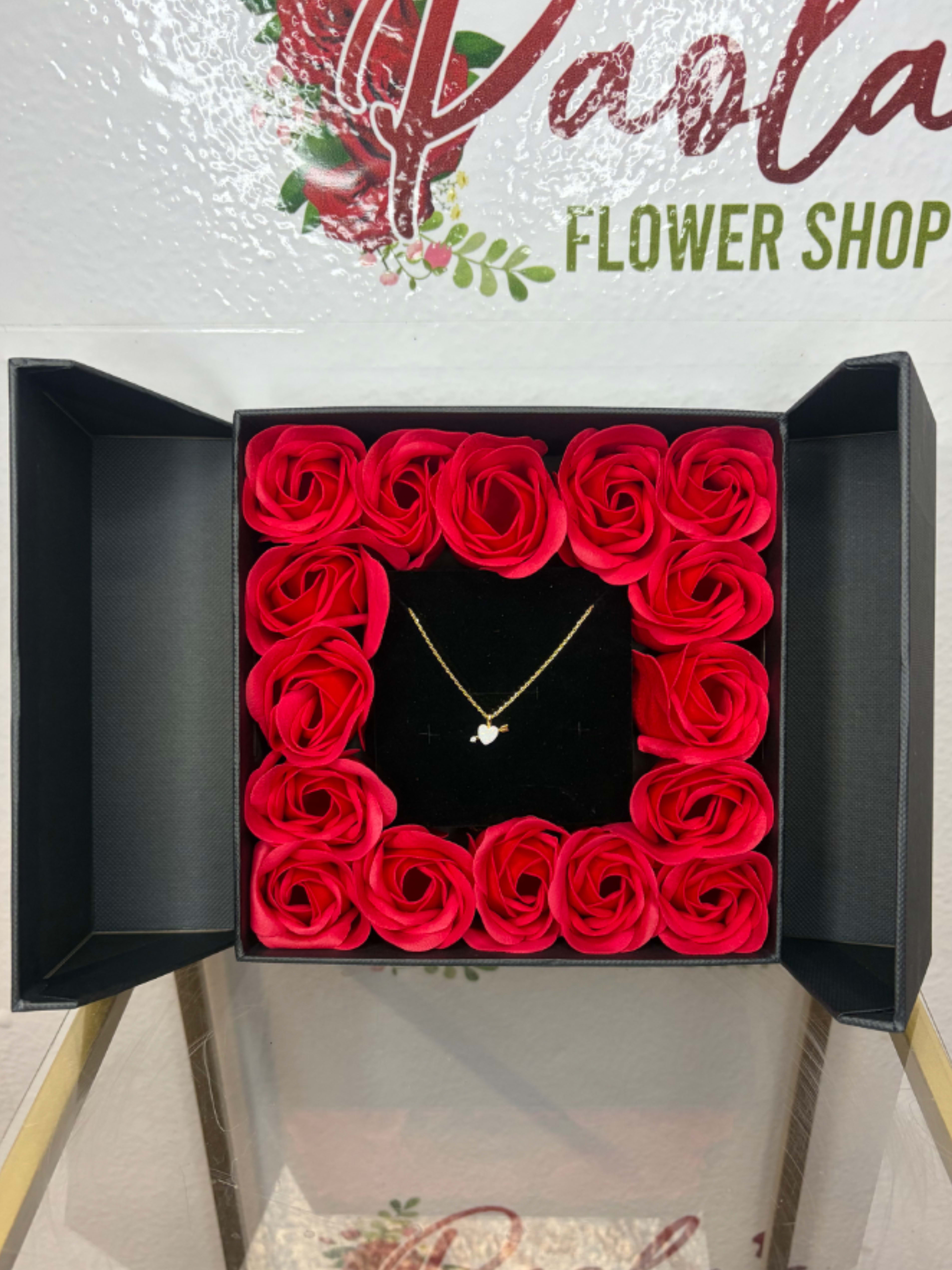 Rose Keepsake Box with Opal Heart Arrow Necklace - A romantic gift that feels like opening a little treasure chest. This elegant black presentation box unfolds to reveal a frame of roses surrounding a delicate gold necklace at the center. The contrast of the deep velvet interior and pastel florals highlights the jewelry beautifully, making it perfect for anniversaries, birthdays, or a heartfelt surprise. Designed to impress the moment it opens — part keepsake, part jewelry display, all charm.  Add a romantic sparkle to your style with this gold opal heart arrow pendant necklace, featuring a luminous heart-shaped opal accented with a delicate gold arrow and a sparkling crystal. Crafted with a polished gold finish, the pendant offers a dreamy, love-inspired design that catches the light beautifully. The fine chain provides lightweight comfort and secures with a lobster clasp, making it perfect for everyday wear or special occasions. A charming piece that blends elegance with sentiment, ideal for gifting or adding a touch of romance to your jewelry collection.  Materials: Gold-plated metal, synthetic opal, crystal Closure: Lobster clasp Style: Romantic, dainty, elegant Ideal for: Everyday wear, gifting, layering  *Not real roses in the gift box, available in pink or red* 