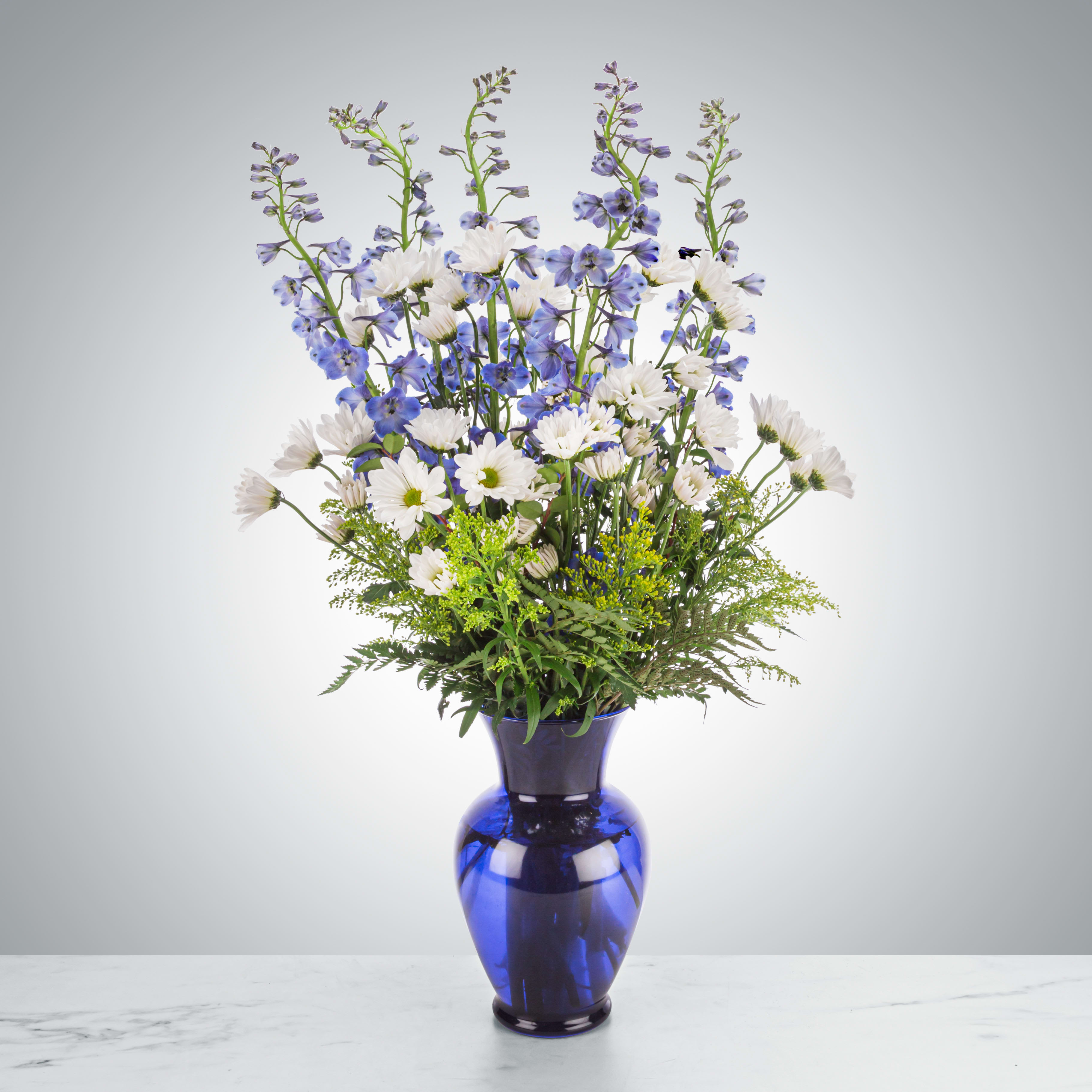 Ahoy There by BloomNation™ - This tall blue and white arrangement is a breezy breath of summer air in an interesting vase. Featuring goldenrod, delphinium, and white daisy poms this arrangement is a sweet summer gesture. Send it for birthdays or as a just-because surprise.  Approximate Dimensions: 18"D X 32"H 