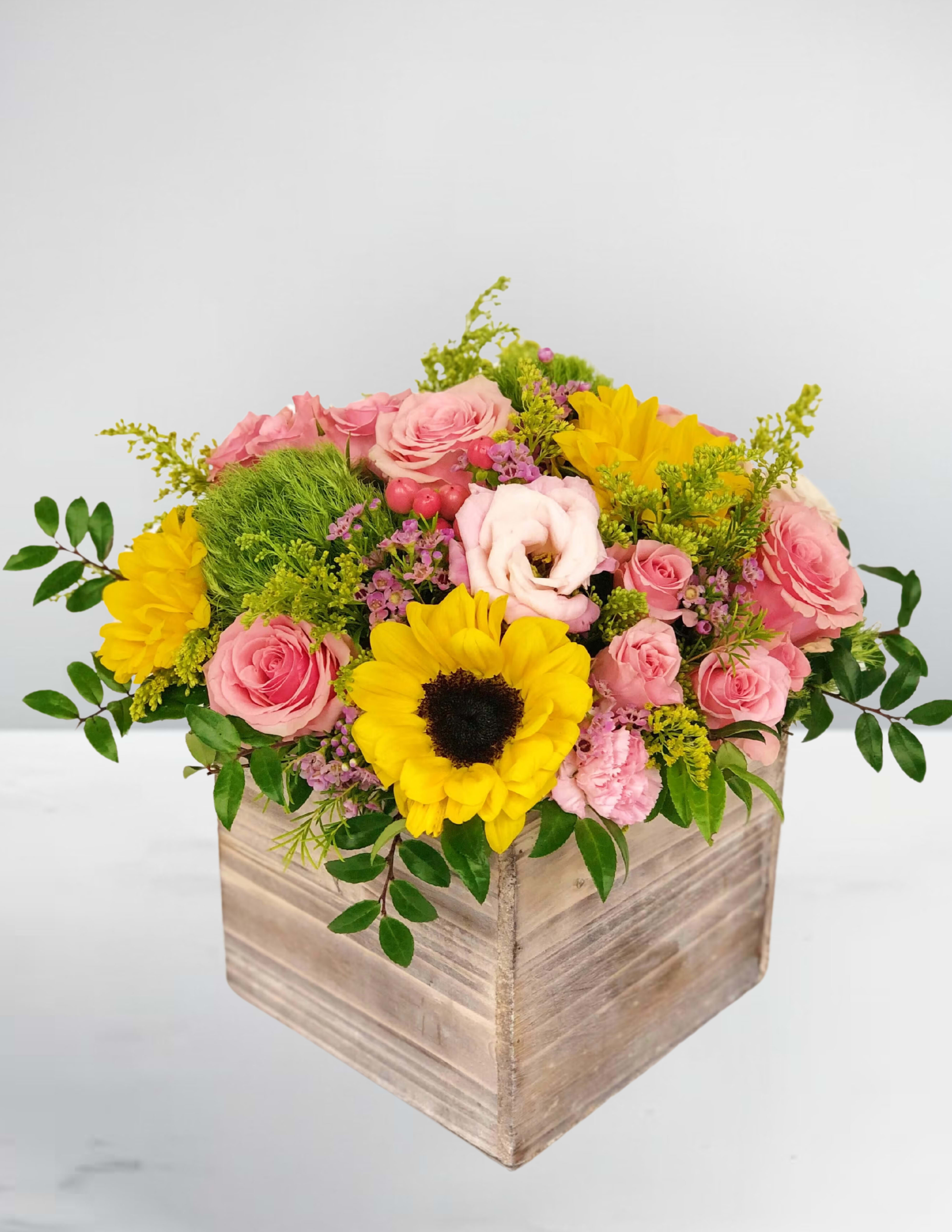 Sweet somethings - Bring sunshine and sweetness to someone’s day with this beautifully rustic arrangement. Vibrant sunflowers radiate warmth and joy, while soft pink roses add a touch of elegance and affection. Nestled in a charming wooden box, this bouquet blends country charm with classic beauty—perfect for Mother’s Day, birthdays, or simply to brighten someone’s space. A heartfelt gift that feels as special as it looks. 