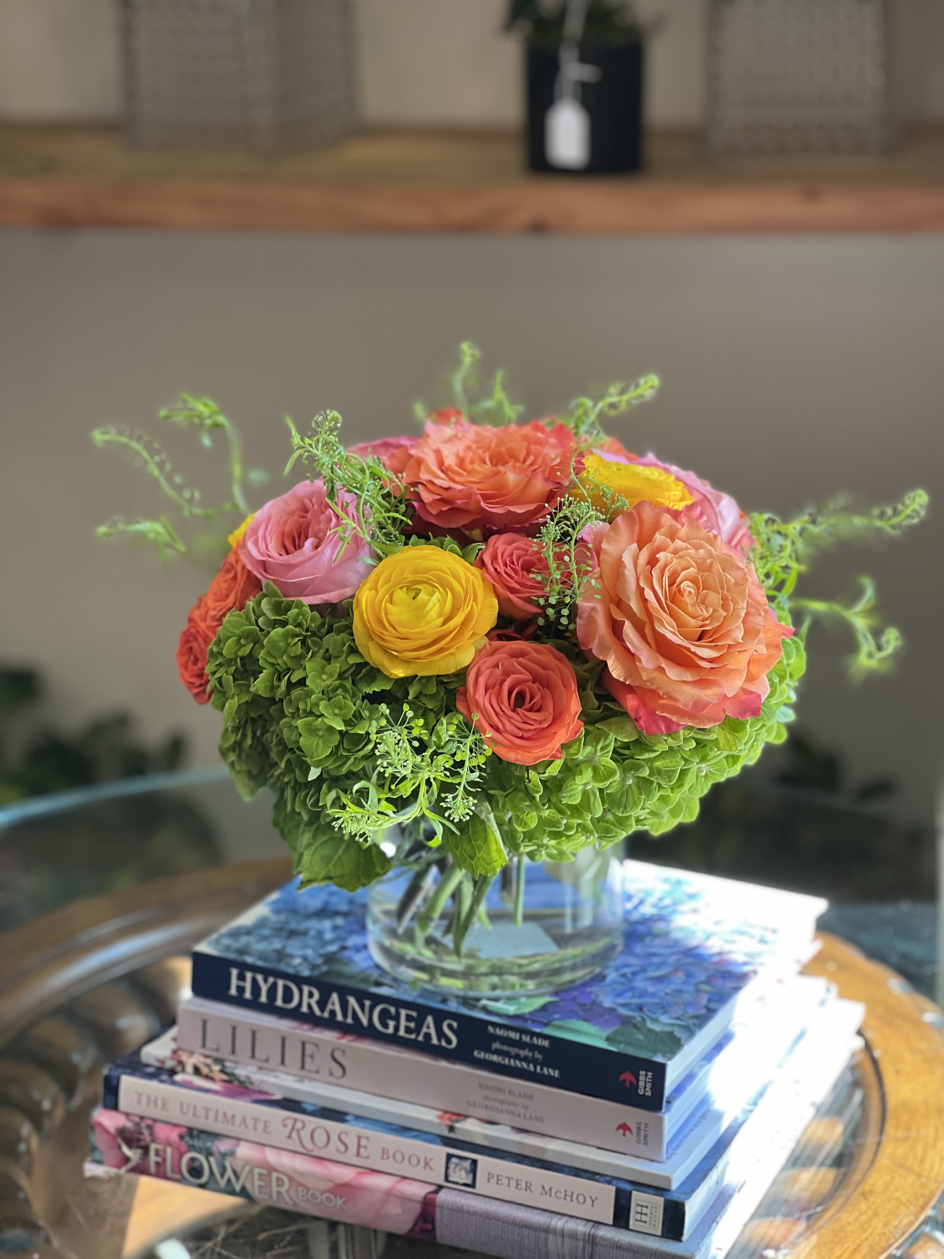 Mango Sorbet  - Florals included: free spirit roses, pink x-pression garden roses, orange spray roses, yellow ranunculus, green hydrangeas, &amp; lepidium greenery accents.  Designed in a 5x5 glass cylinder.