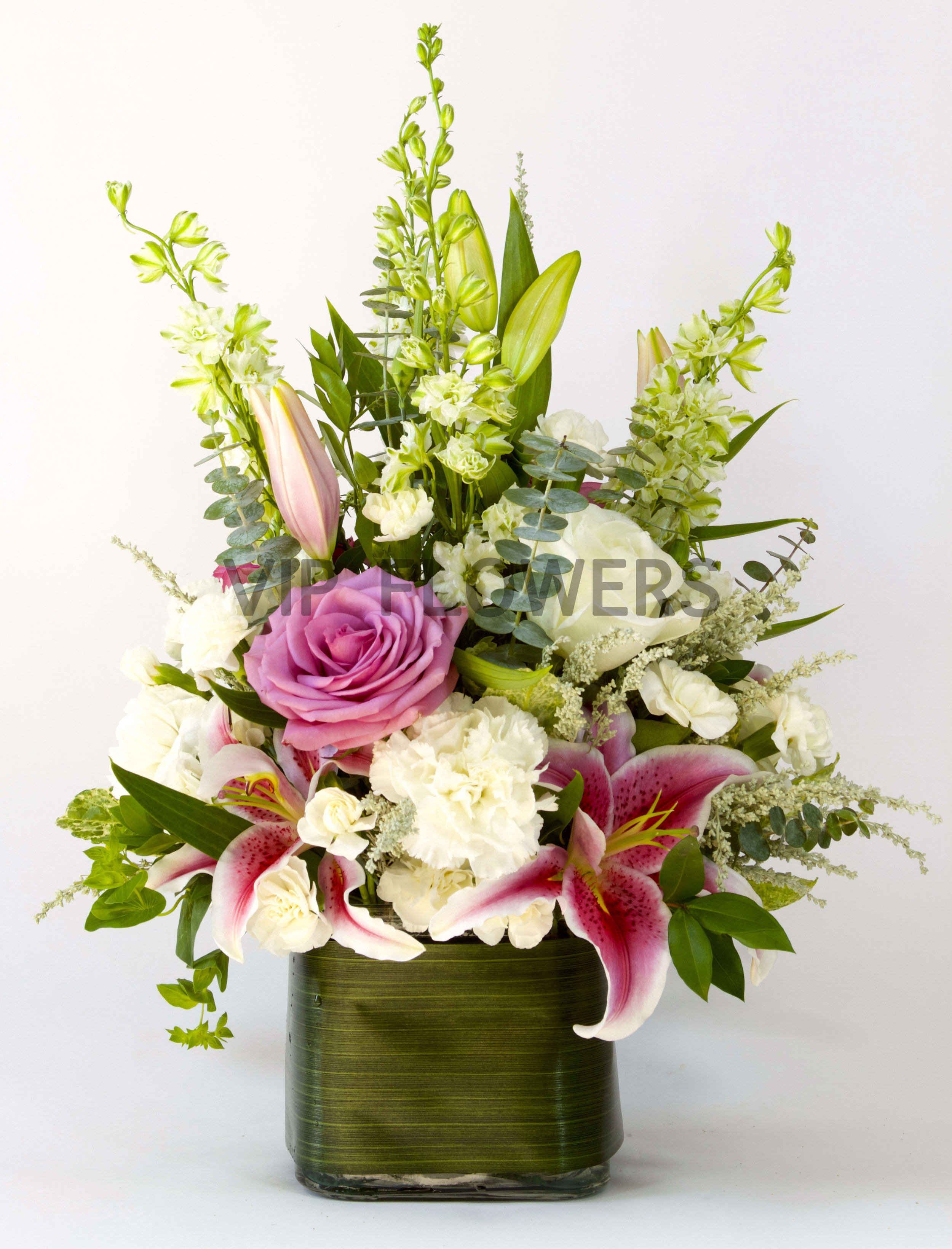 Simplistic Grace - Flowers Included:  Roses Lilies Carnations Larkspur Seasonal Flowers Seasonal Greens       Substitutions may be necessary to ensure your arrangement or specialty gift is delivered in a timely manner. The utmost care and attention is given to your order to ensure that it is as similar as possible to the requested item (Please note that some flowers and colors may vary due to seasonality.)