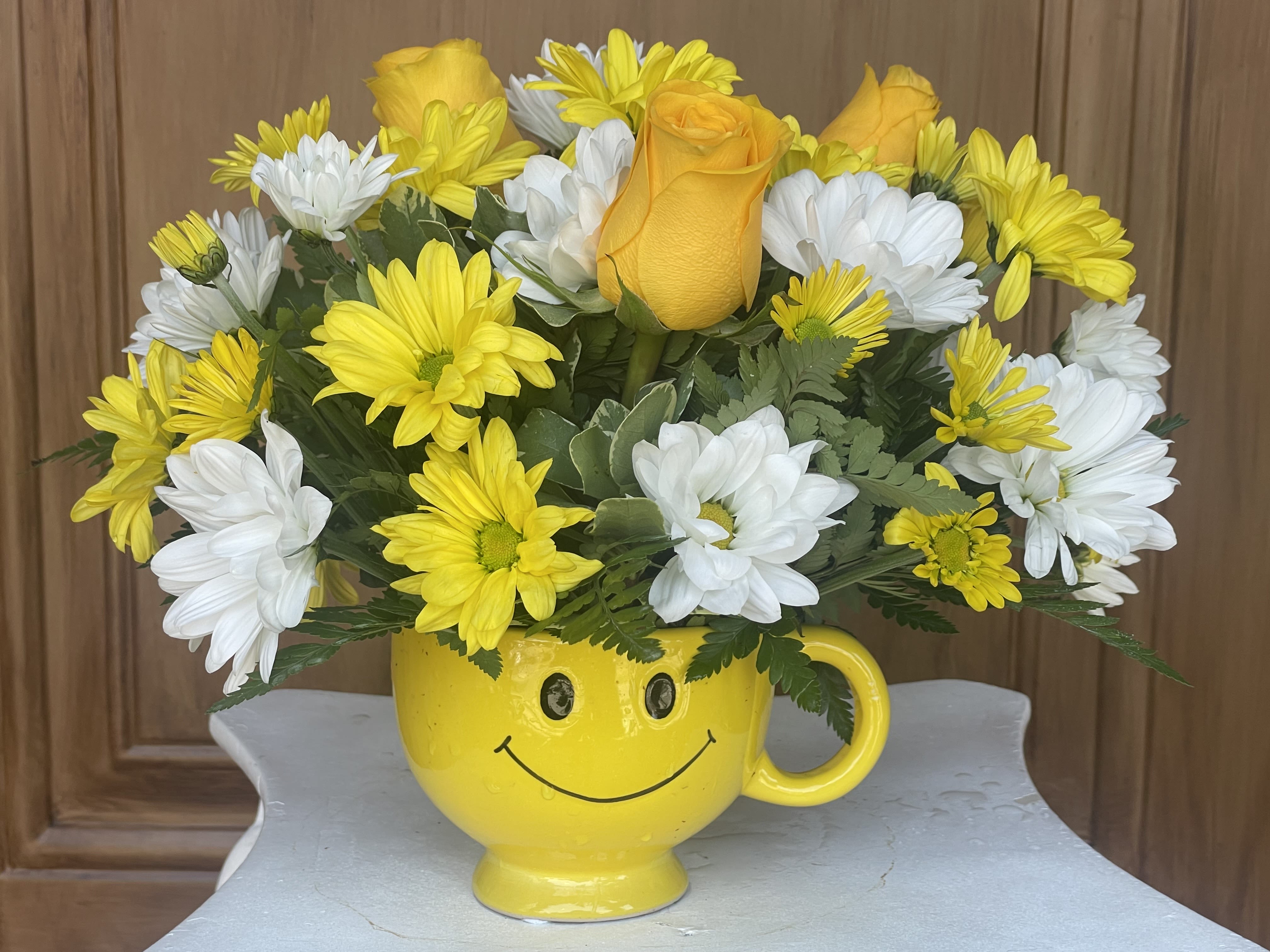 Don't Worry Be Happy   - Brighten someone's day with this sweet happy face mug filled with white and yellow daisies and yellow roses. Perfect for everyday gift giving. 