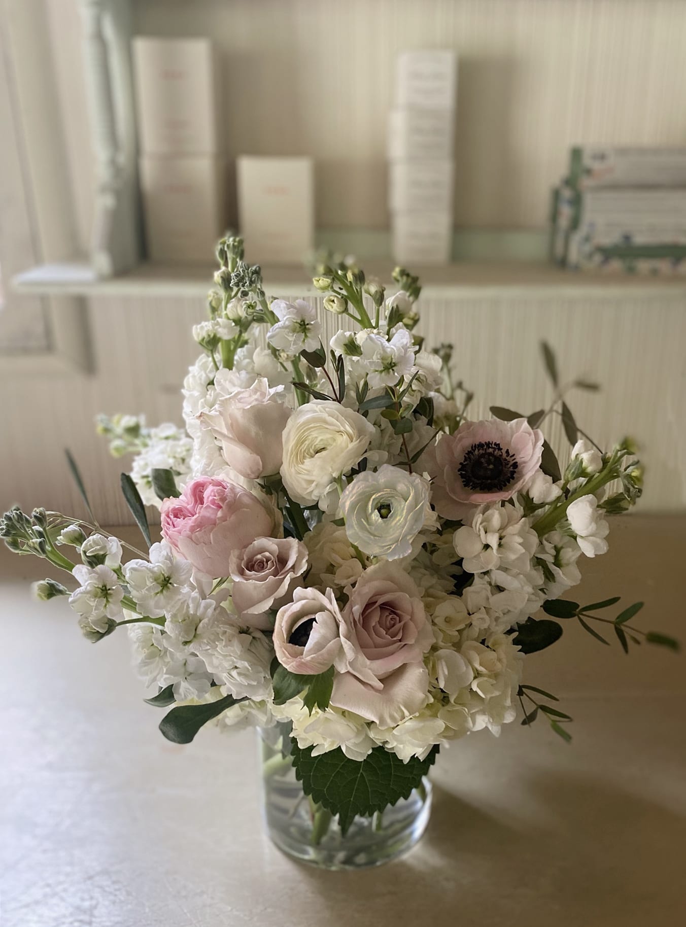 Stella - Light, classic, wild and elegant arrangement of all whites and greens, with some nude and blushing tones. Garden roses, anemones, ranunculus and other forgeous stems of the season mixed with beautiful natural green stems. For the stylish recipient who needs a lovely floral vase for the kitchen, dinner table, the night stand or anywhere, really, where fresh, pretty flowers are needed. Arranged in a clear 5 by 6 vase.  Go Delue for more stems in same size vase or Premium for more volume, in larger vase.