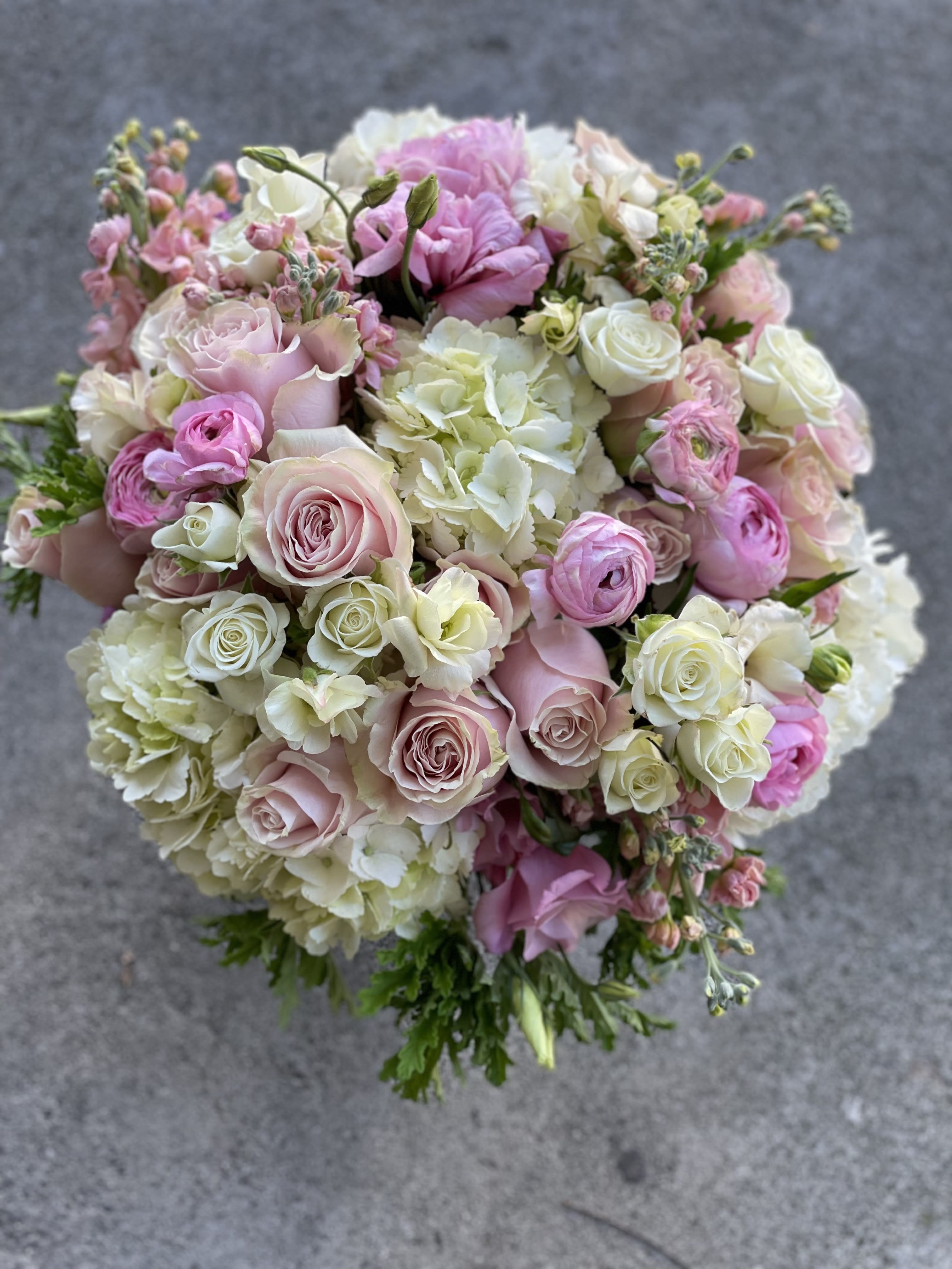 Isn't She Lovely  - This is a designer's choice in pink and white with touches of greens. Lush arrangement of pinks and whites filled with blooms in a low cylinder vase.  We pick the blooms, you pick the size. Pictured here is our deluxe birds eye view.     Standard- Side table, desk, vanity, Standard small.  Deluxe- (Pictured) Dinner table, coffee table   Premium- Premium blooms added and it will have the largest footprint suitable for a large coffee table, entry way, or credenza  NOTES: We will choose the freshest and most interesting ingredients at the market to make this arrangement shine. Vessels may be substituted depending on availability.   If any design element such as color or flower/foliage are very important to your order please contact us to ensure availability first by calling the shop at  415 751 2747 