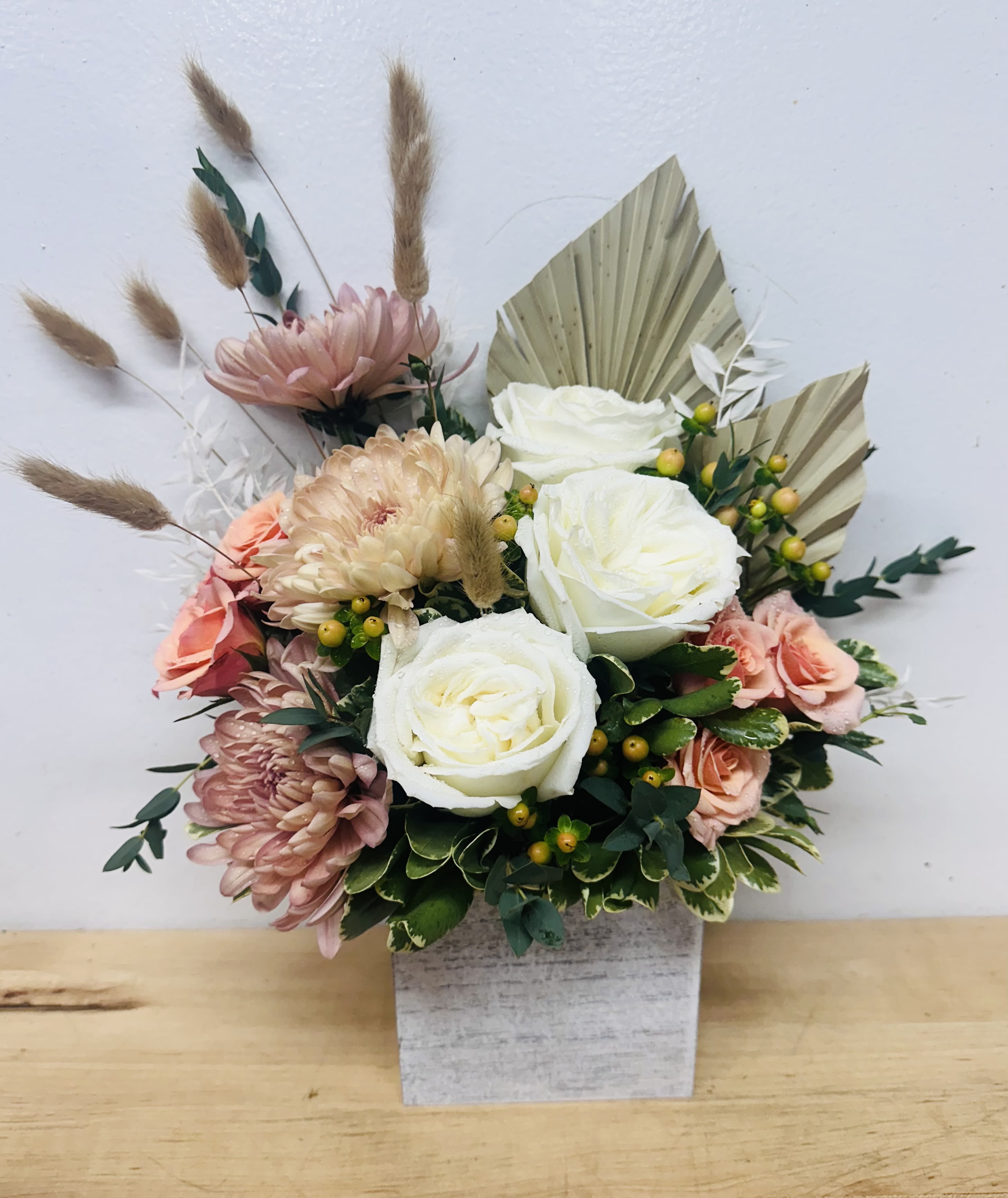 Desert Bloom - Earthy meets elegant in this textured arrangement of soft white roses, blush mums, dried elements, and preserved palms. with warm desert tones and modern boho vibes, Desert Bloom is perfect for those who love a natural, curated look with a touch of whimsy.