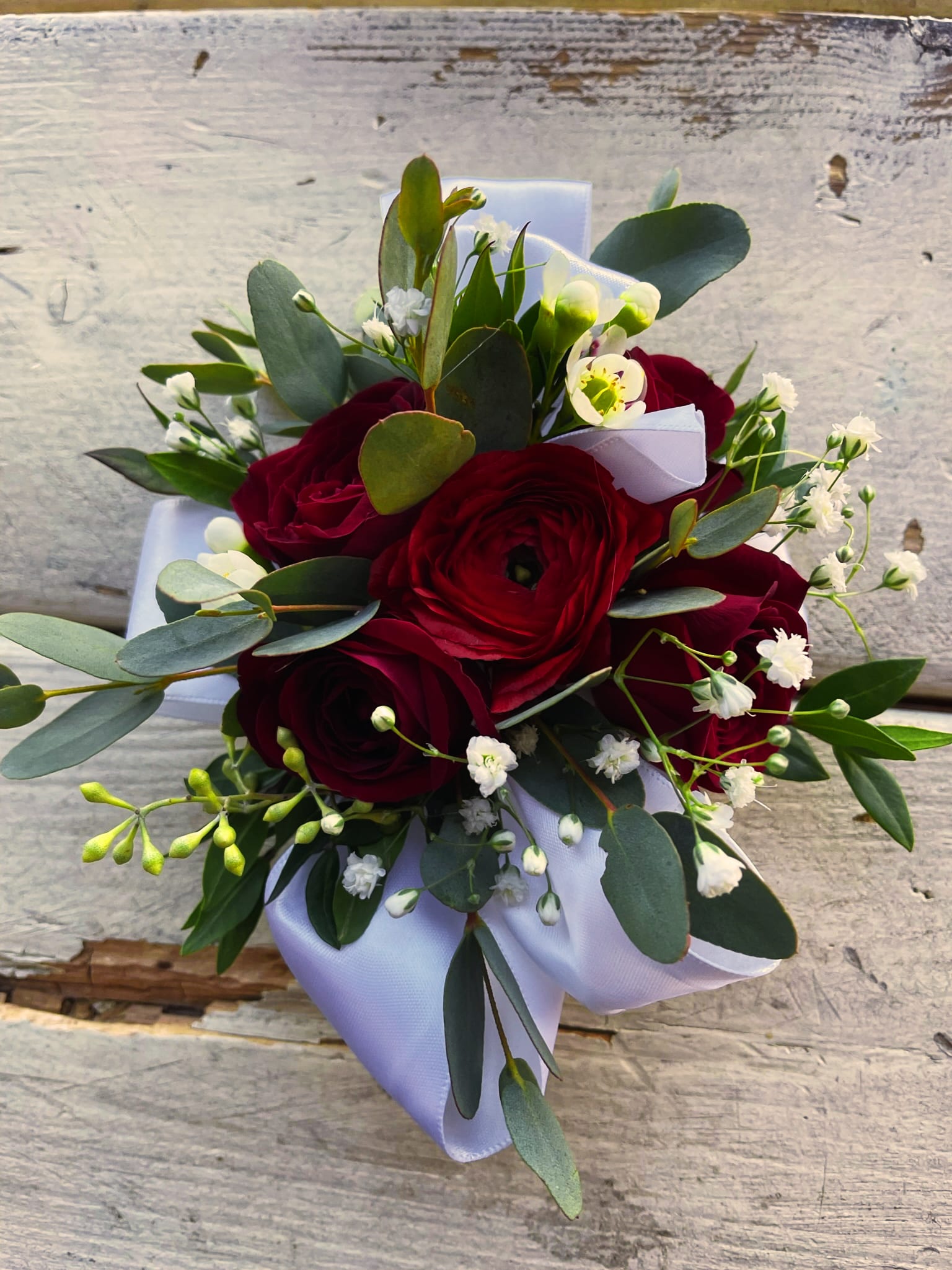 Wrist Corsage #3 Roses and Ranunculus - Red spray roses, ranunculus, greenery variety and filler. Please specify ribbon color