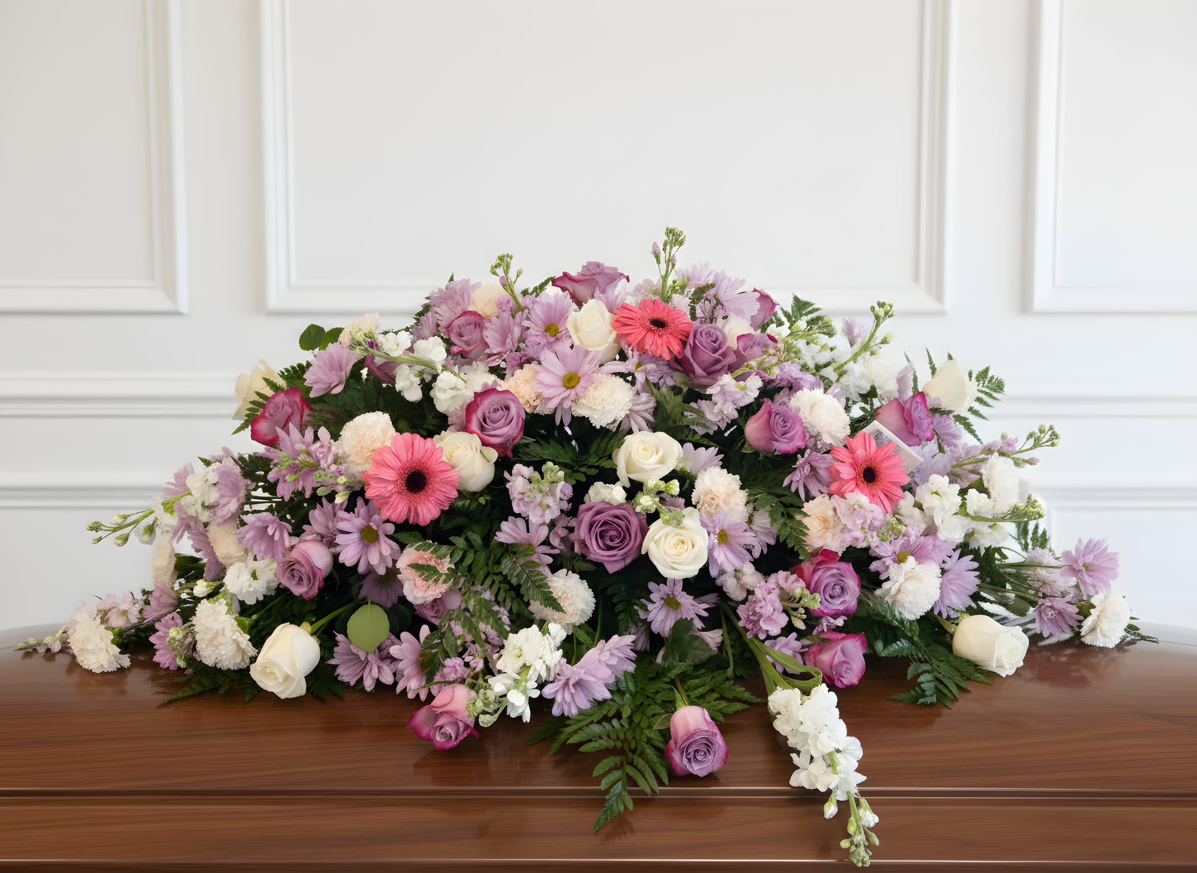Whispering Comfort Casket Spray - A soft and elegant casket spray designed with lavender, white, and pink blooms accented with fresh greenery. This peaceful tribute symbolizes grace, love, and comfort, offering a gentle and heartfelt farewell.