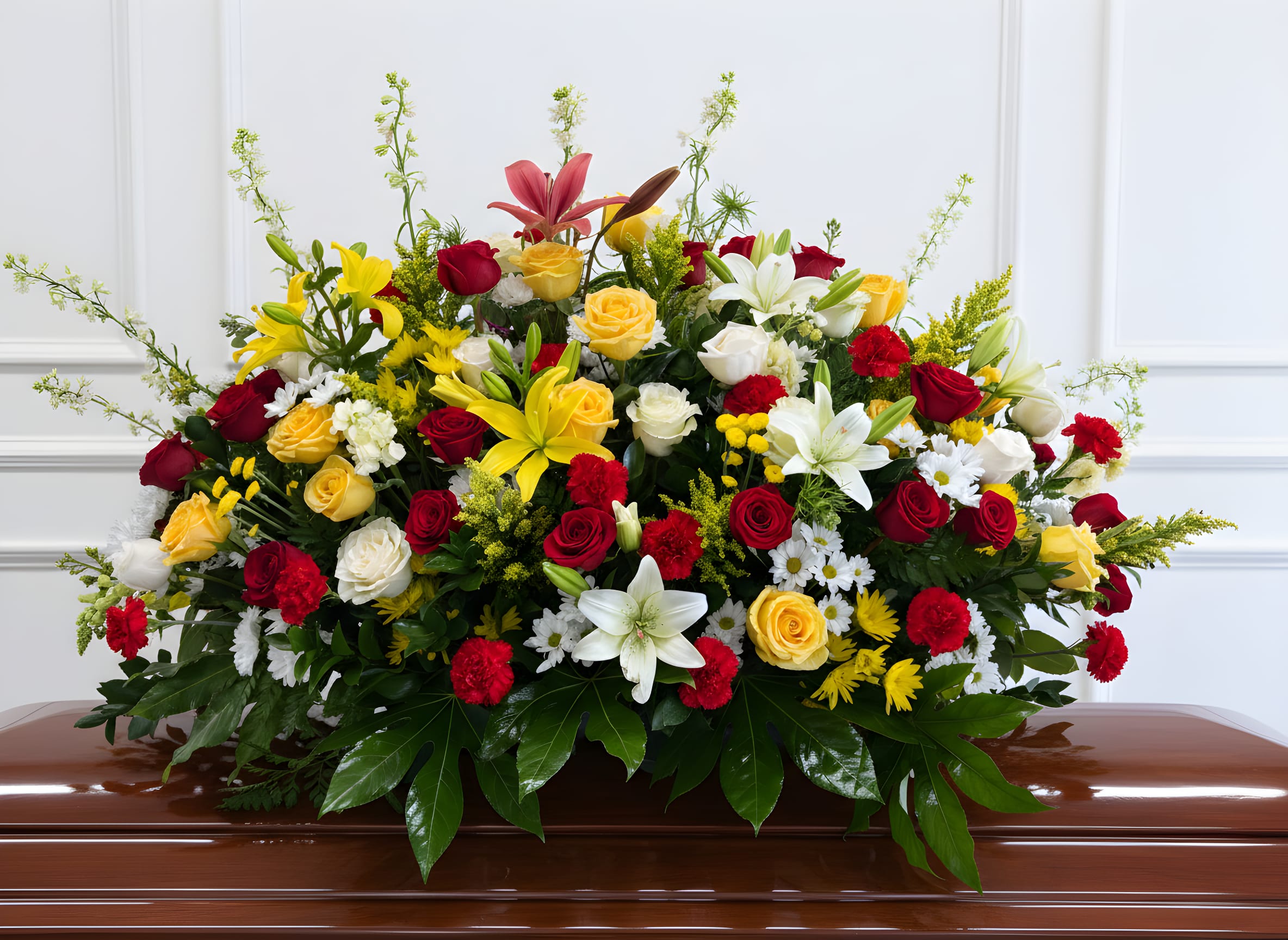 Bright Legacy Tribute Casket Spray - A full and large casket spray featuring vibrant yellow, rich red, and pure white blooms beautifully arranged with lush greenery. This bold and heartfelt tribute symbolizes honor, love, and celebration of a life well lived, offering a warm and meaningful farewell.