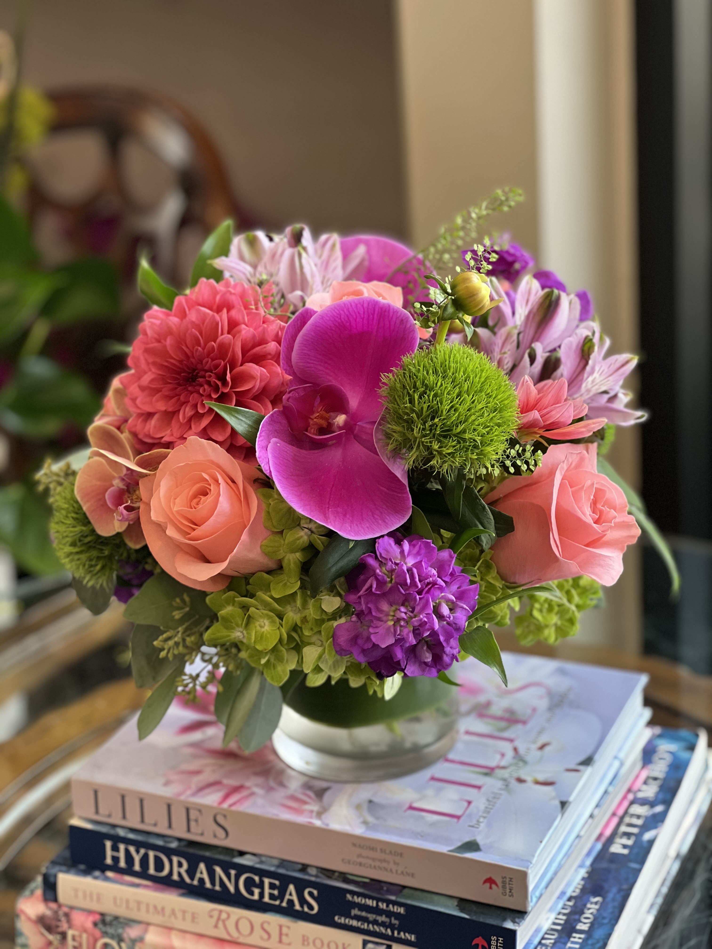 Purple Poppi  - flowers: purple orchids, be sweet roses, green hydrangea, alstromeria lavender, stock purple, lipidium greenery, seeded eucalyptus.   In a 5x5 glass cylinder vase. 