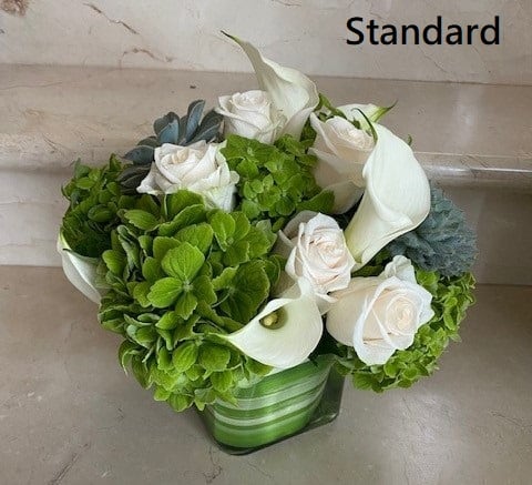 Summer Breeze - Green and White Elegant Arrangement with Green Hydrangeas, white roses, white callas, succulents and more. Arranged round in a glass Vase.