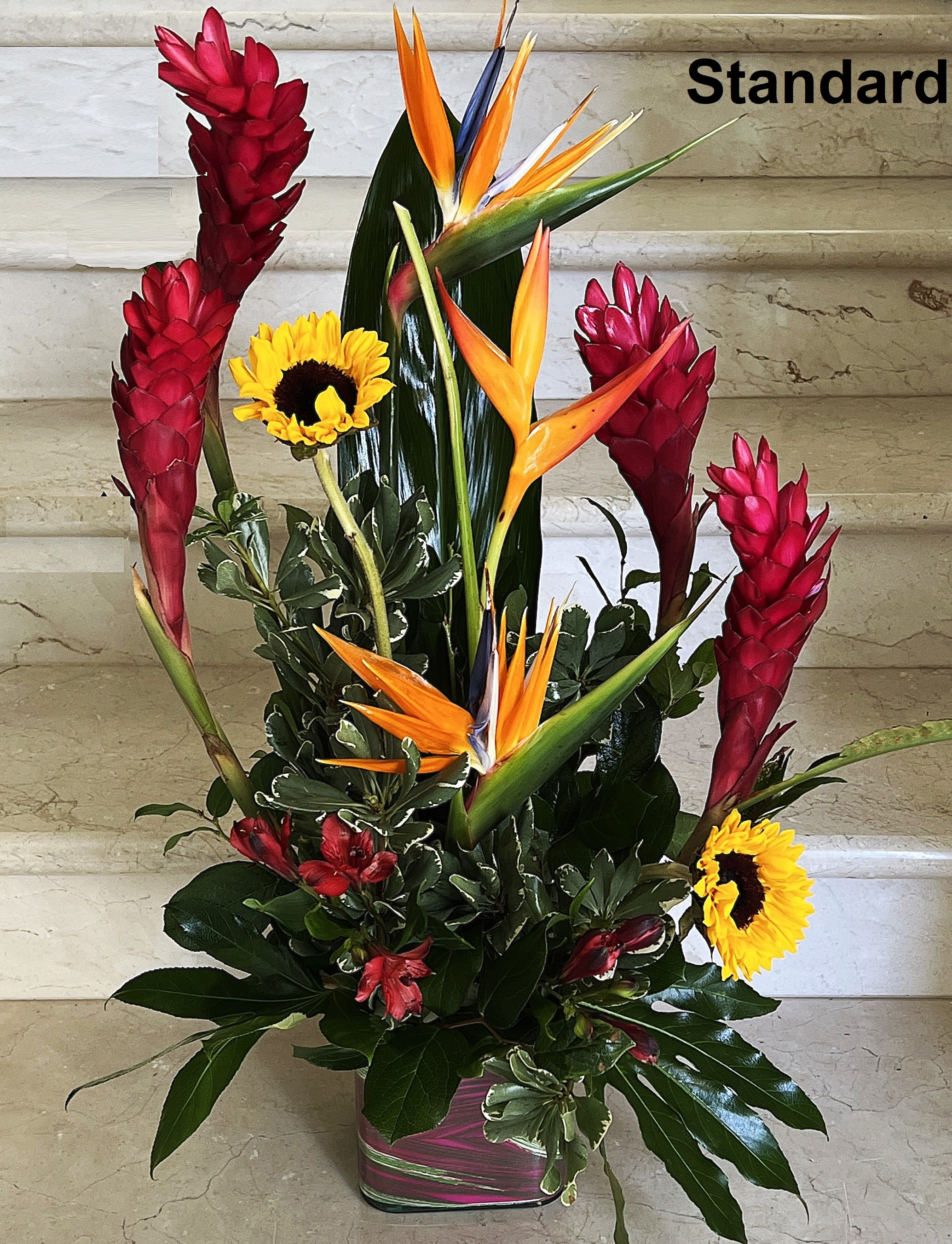 Airy and Bright - Tropical flowers as shown arranged in a vase. The quantity of flowers increase with Deluxe and more for Premium with a larger vase.   