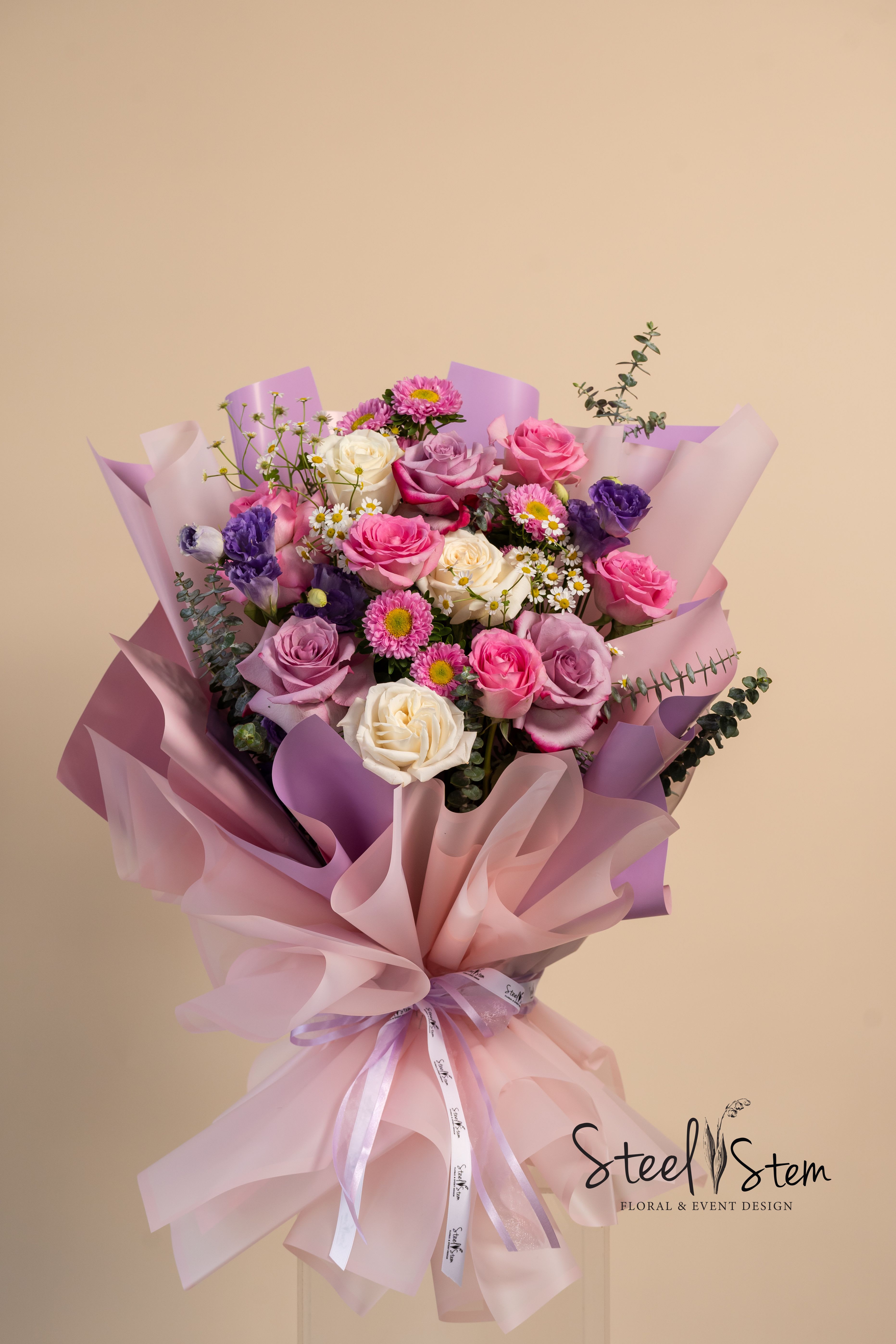 Blossom at dawn wrap bouquet  - Like the first light of morning, Blossom at Dawn is a bouquet that awakens the senses with soft, radiant beauty. Wrapped in elegant in pastel tones, this arrangement features a delicate blend of lavender roses, blush pink blooms, white roses, and touches of violet. The gentle hues and airy textures create a dreamy, romantic feel—perfect for celebrating love, new beginnings, or simply brightening someone’s day. Designed to be displayed as is, Blossom at Dawn requires no unwrapping, making it effortlessly beautiful and ready to be enjoyed from the moment it arrives.