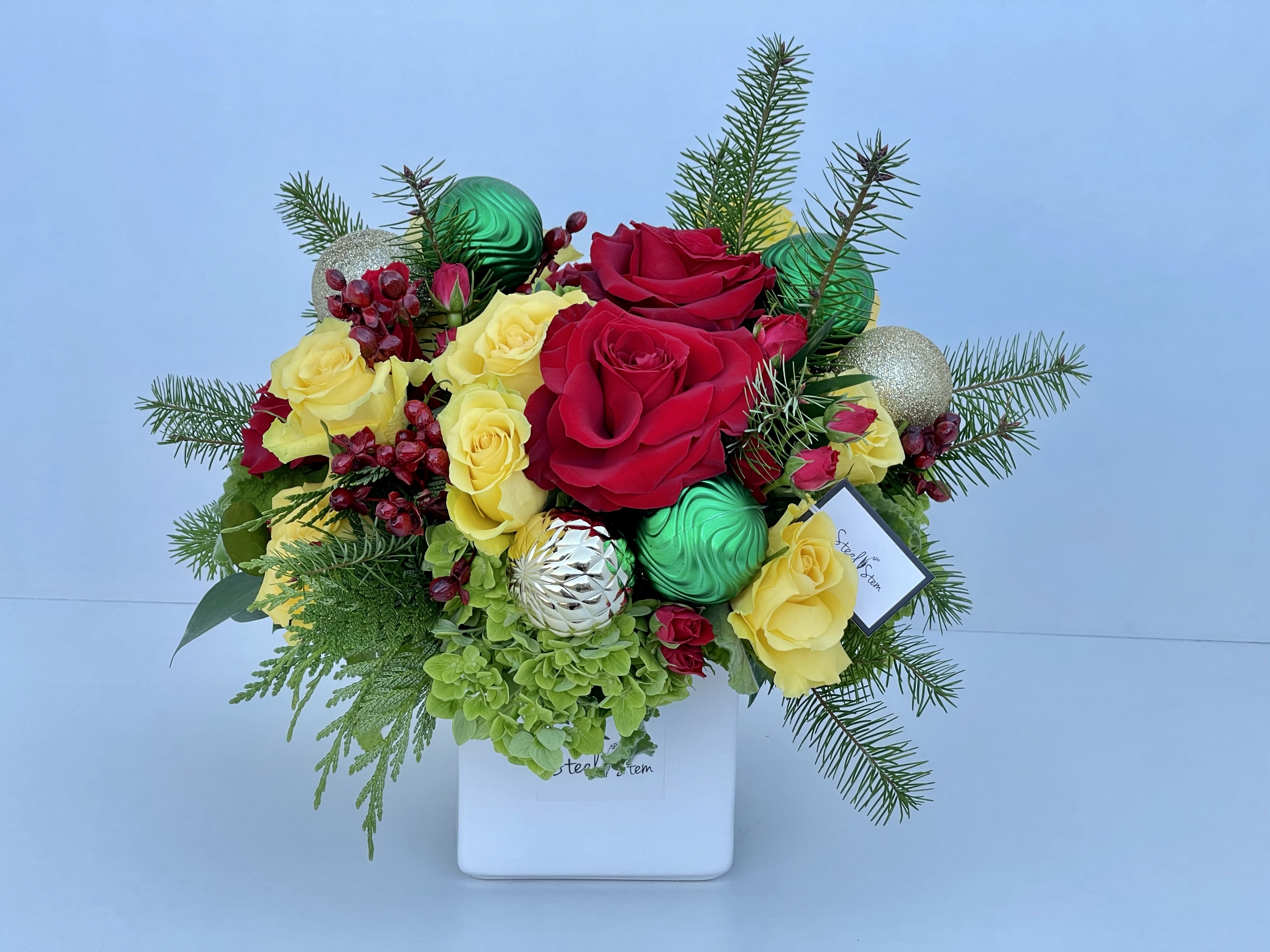 Cheerful Christmas  - Merry Christmas! Happy Holidays! Say it with our Cheerful Christmas arrangement. Made of fresh Christmas Greens, red roses, yellow roses, premium green hydrangeas, gold ornaments, green ornaments and a high quality white square glossy ceramic vase. It's a perfect statement piece!