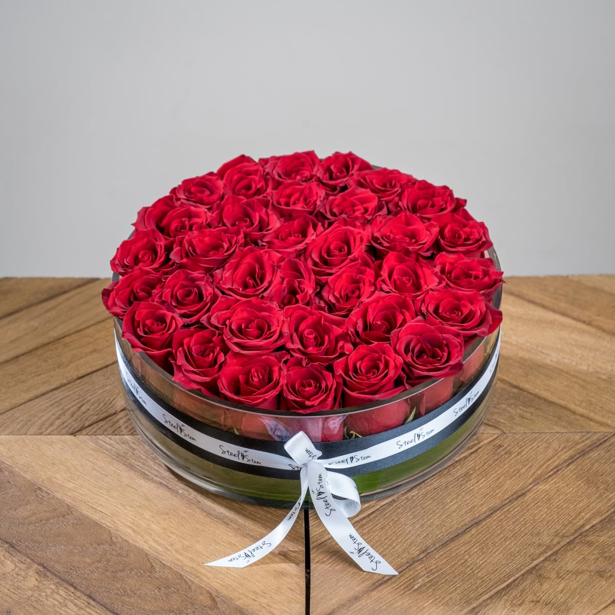 Rouge Luxury - A low and wide classic glass cylinder with thirty three traditional, romantic red roses. Our Rogue Luxury is the perfect statement piece to confess your true love to your special person this Valentine's Day.  This easy to care for arrangement will make the perfect centerpiece for any dining table or coffee table. Be sure to add water daily!  Measures approx. 12"Wx5"H