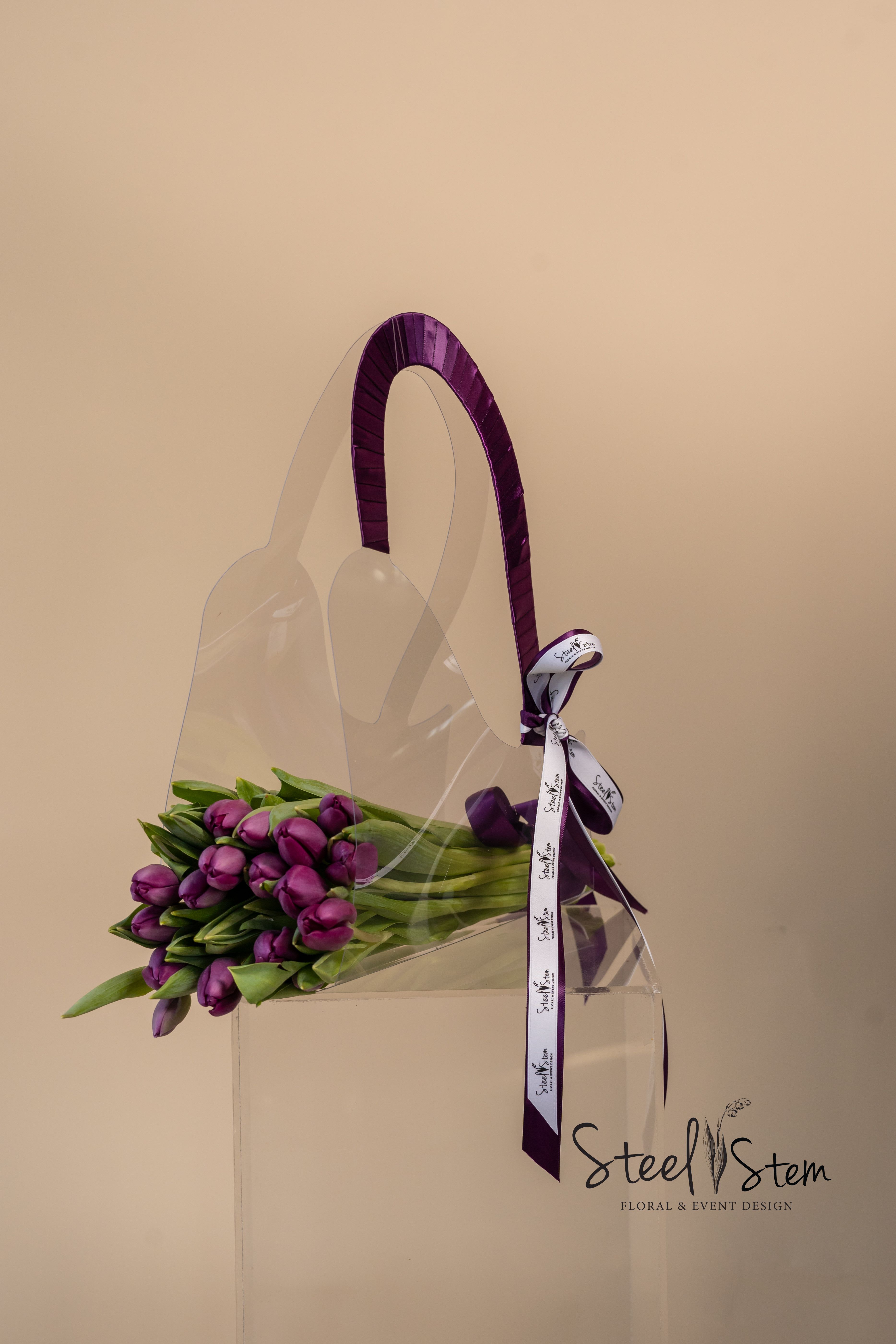 Purple Tulip Tote Collection  - Purple Tulip Tote Bouquet is the elegance and sophistication, designed for those who appreciate both beauty and style. This exquisite bouquet features fresh, hand-selected tulips, carefully arranged and tied with a luxurious purple ribbon for a refined finish. Presented in a high-end, elegantly crafted tote-style bag, this bouquet transforms floral gifting into a statement of luxury. The tote’s sleek design and premium details make it a stunning complement to the vibrant tulips, creating a truly unforgettable presentation. Perfect for any occasion, the Purple Tulip Tote Bouquet is a timeless expression of grace and refinement.