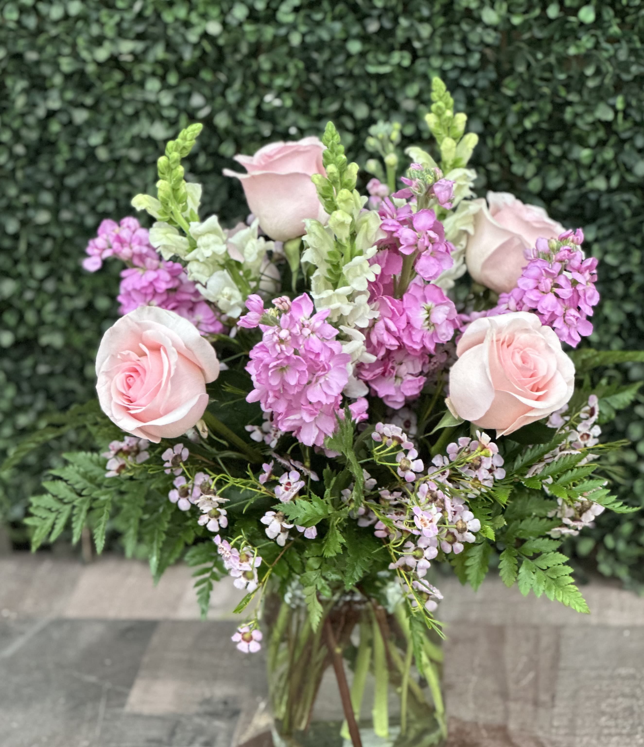 MOTHER'S GARDEN - A tridiagonal design in a glass vase with roses, snapdragons, stock and wax flower. 