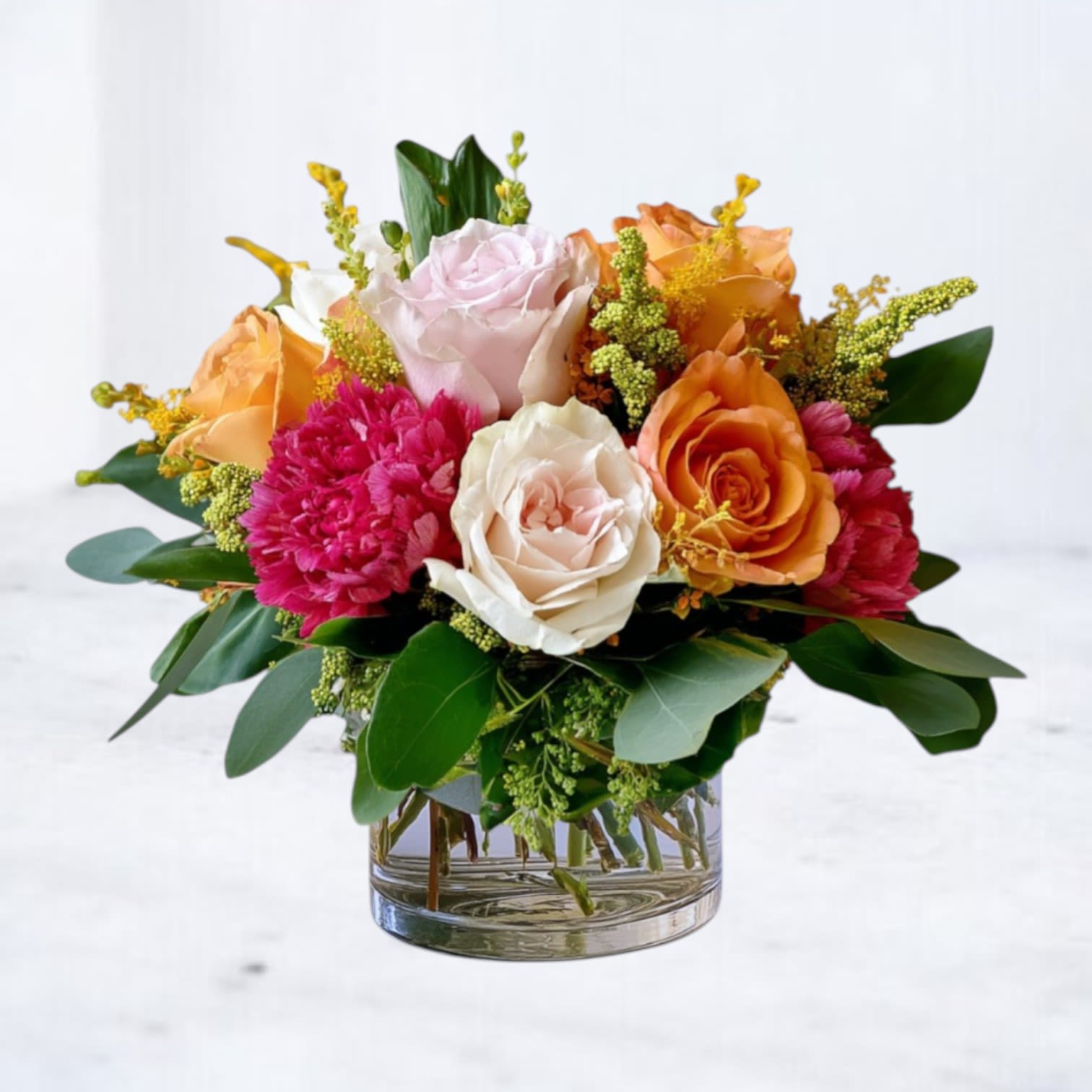 Petal Play - Petal Play is a thoughtfully designed arrangement meant to offer warmth, comfort, and quiet beauty — perfect for moments when a gentle gesture speaks louder than words.  Featuring a harmonious mix of light pink and orange roses, hot pink carnations and lush greenery, this design is arranged in a modern clear glass vessel with a relaxed, garden-inspired feel. The palette is uplifting yet calm, making it an ideal choice for a wide range of occasions.  Whether sent as a thoughtful surprise, a message of support, a thank-you, or simply to brighten someone’s day, Petal Play delivers beauty with intention and grace.