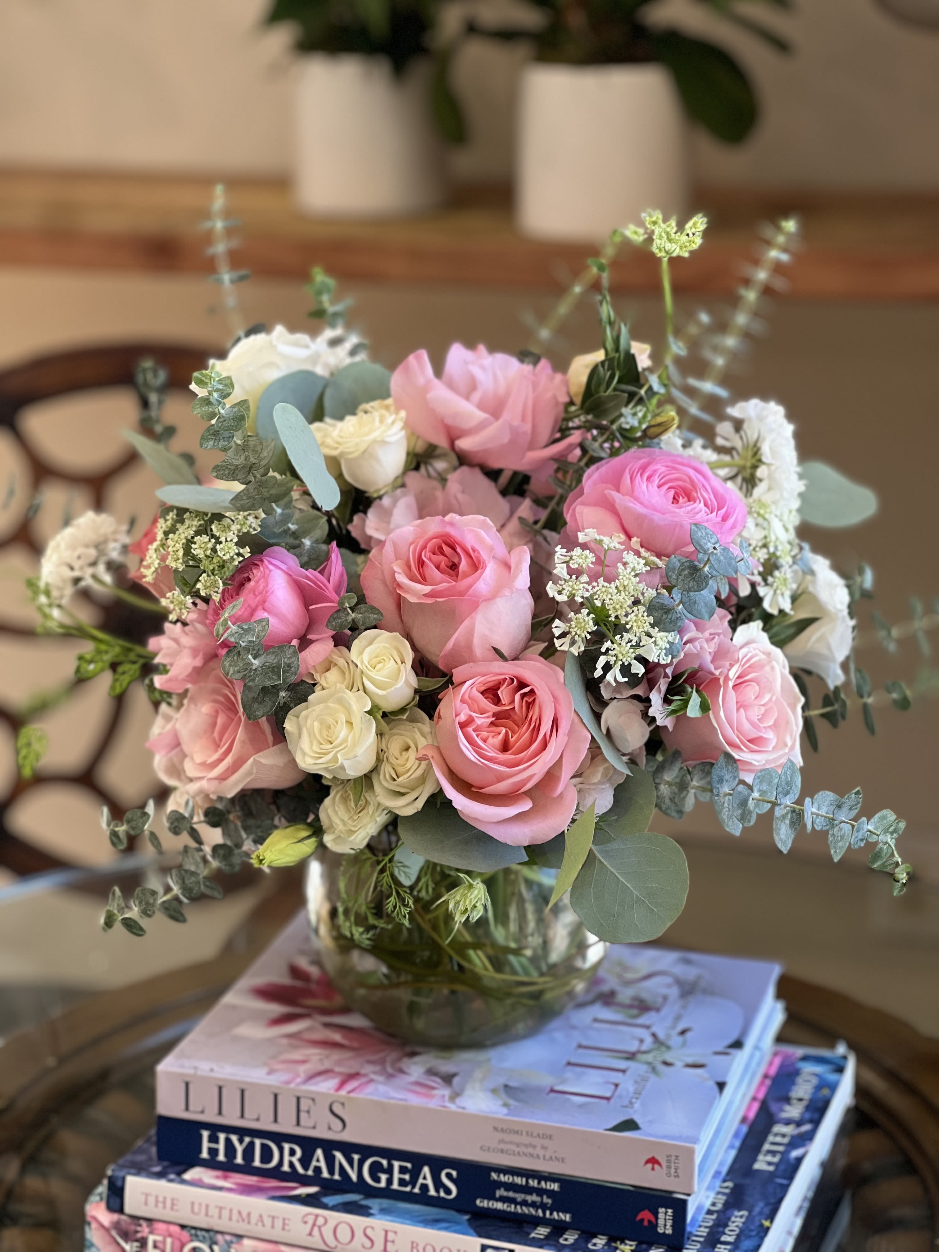 Rose Quartz Heart  - Flowers: pink xpression garden roses, white spray roses, pink ranunculus, frutetto roses, white scabiosa, orlaya flower, babye blue eucalyptus, and silver dollar eucalyptus.   Arranged in a small fishbowl glass vase decorated with curly willow