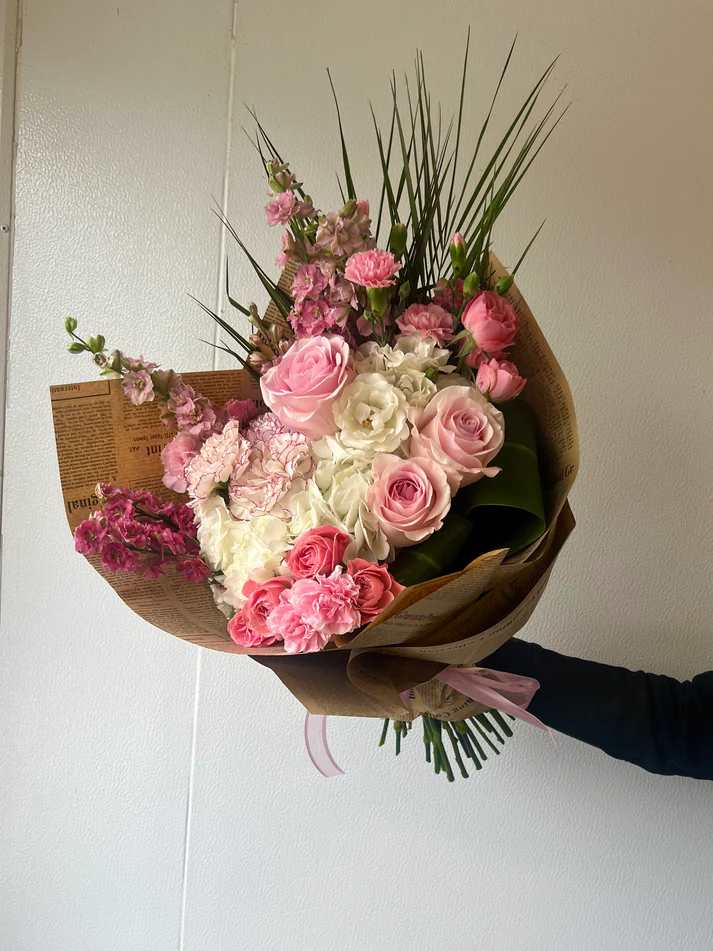 Sweet Komachi  - Our “Sweet Komachi” bouquet is soft, beautiful and rosy! The word “Komachi” means “beautiful lady” and “feminine beauty” in Japanese. Cute and flirty, florals included in this bouquet are cloudy white hydrangeas, light pink larkspur, komachi carnations, mini carnations, novia roses, mini spray roses, and accents of palm leaves. Wrapped in our signature newspaper brown craft paper and topped with a pretty pink ribbon.