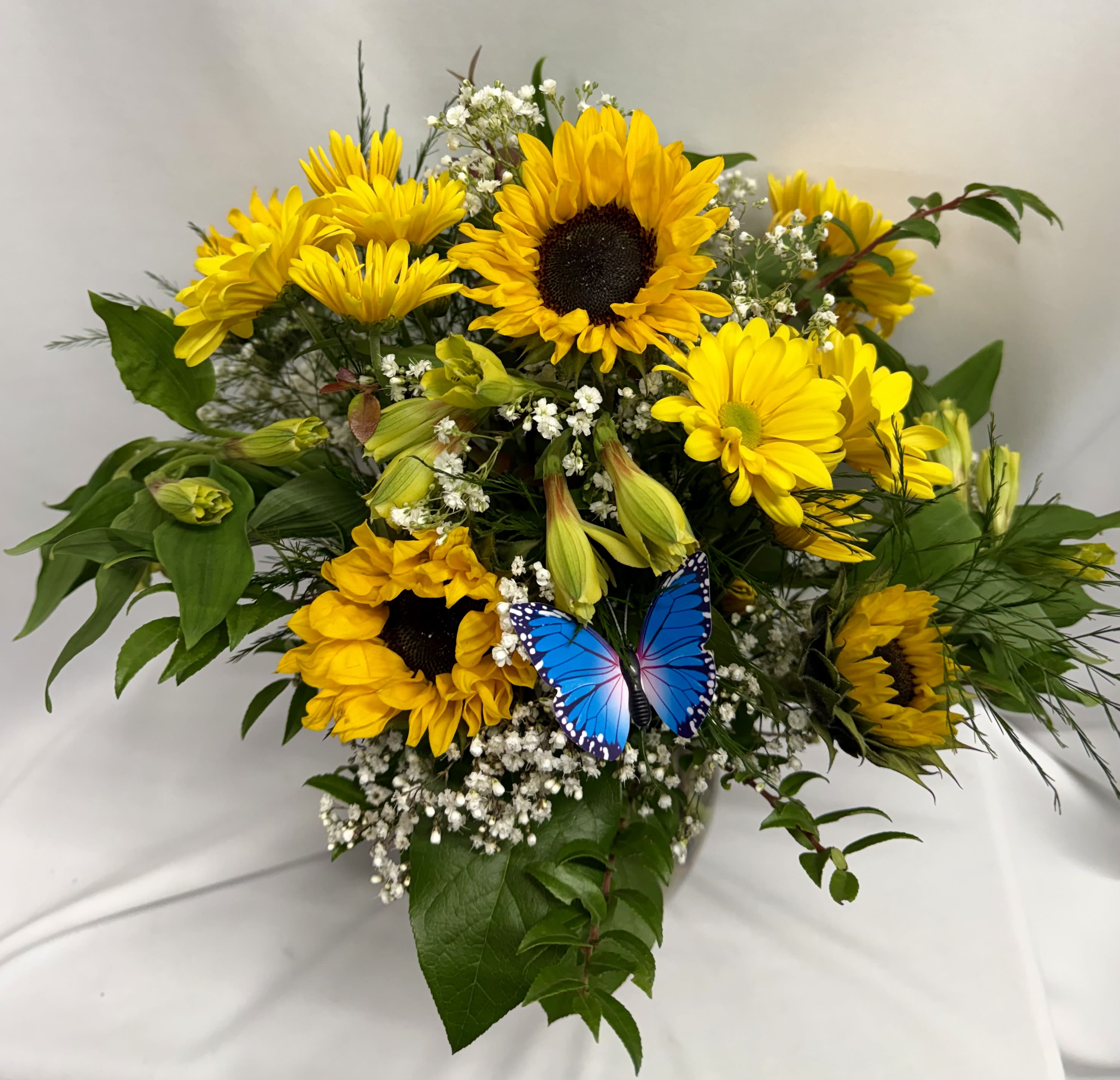 Sunshine and Sunflowers - Sunflowers let's face it, are a happy flower any time of year. They are great in the Summer months, but they can really help us get through some dark Autumn days. We created this flower arrangement to be overflowing with sunshine for anyone you send it to... or maybe even just for yourself for a special treat. We mix these brightly happy flowers with other bright yellow seasonal blooms, alstroemeria and daisies for example. Let’s not forget a brightly colored butterfly too!