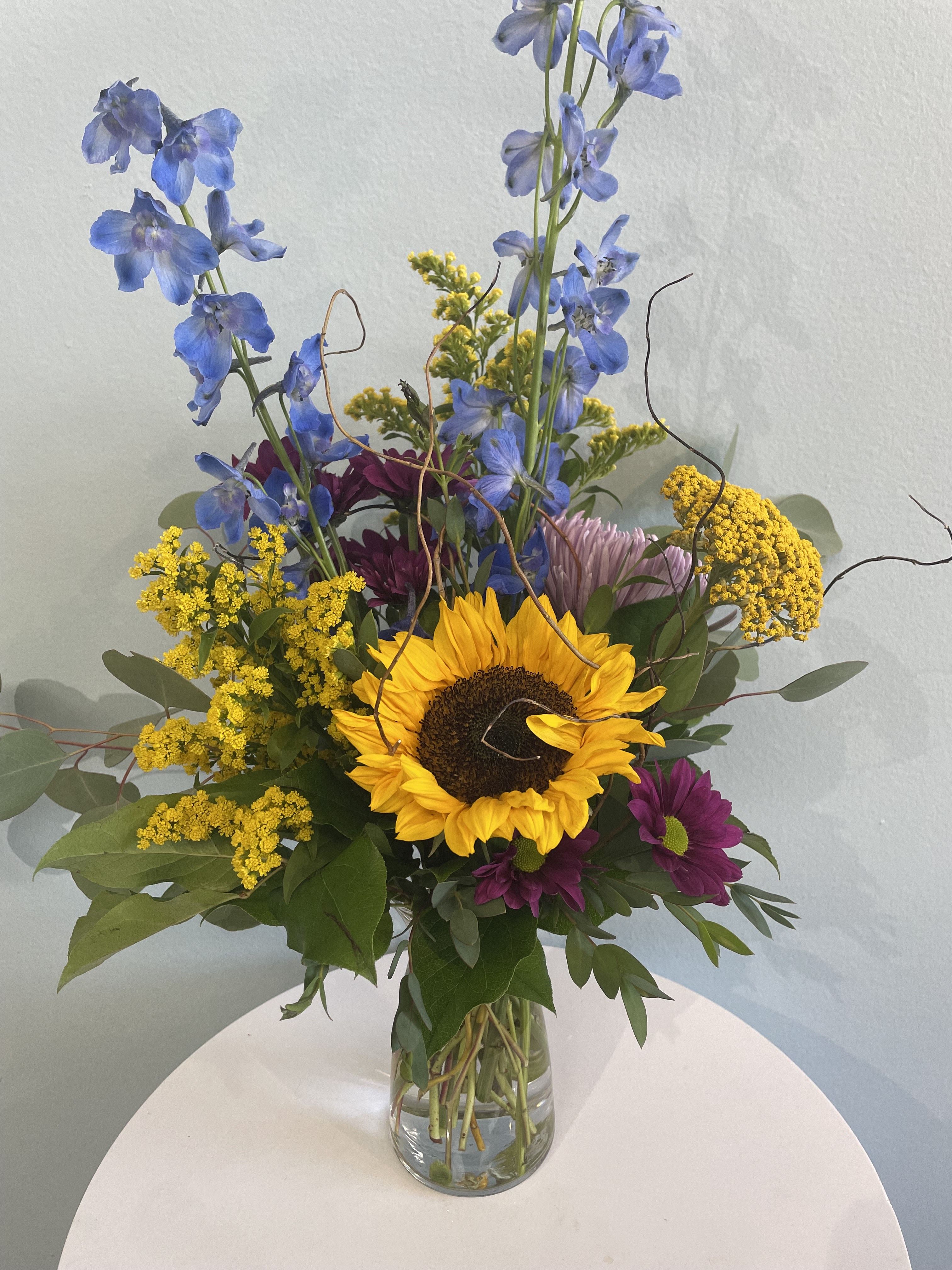 Wild Beauty - This small mix of wildflowers is the perfect gift for someone who loves nature and the outdoors. This colorful mix may include a sunflower, delphinium, and yarrow. Resembling a flower field, this arrangement is perfect for bringing nature into someone's life. 
